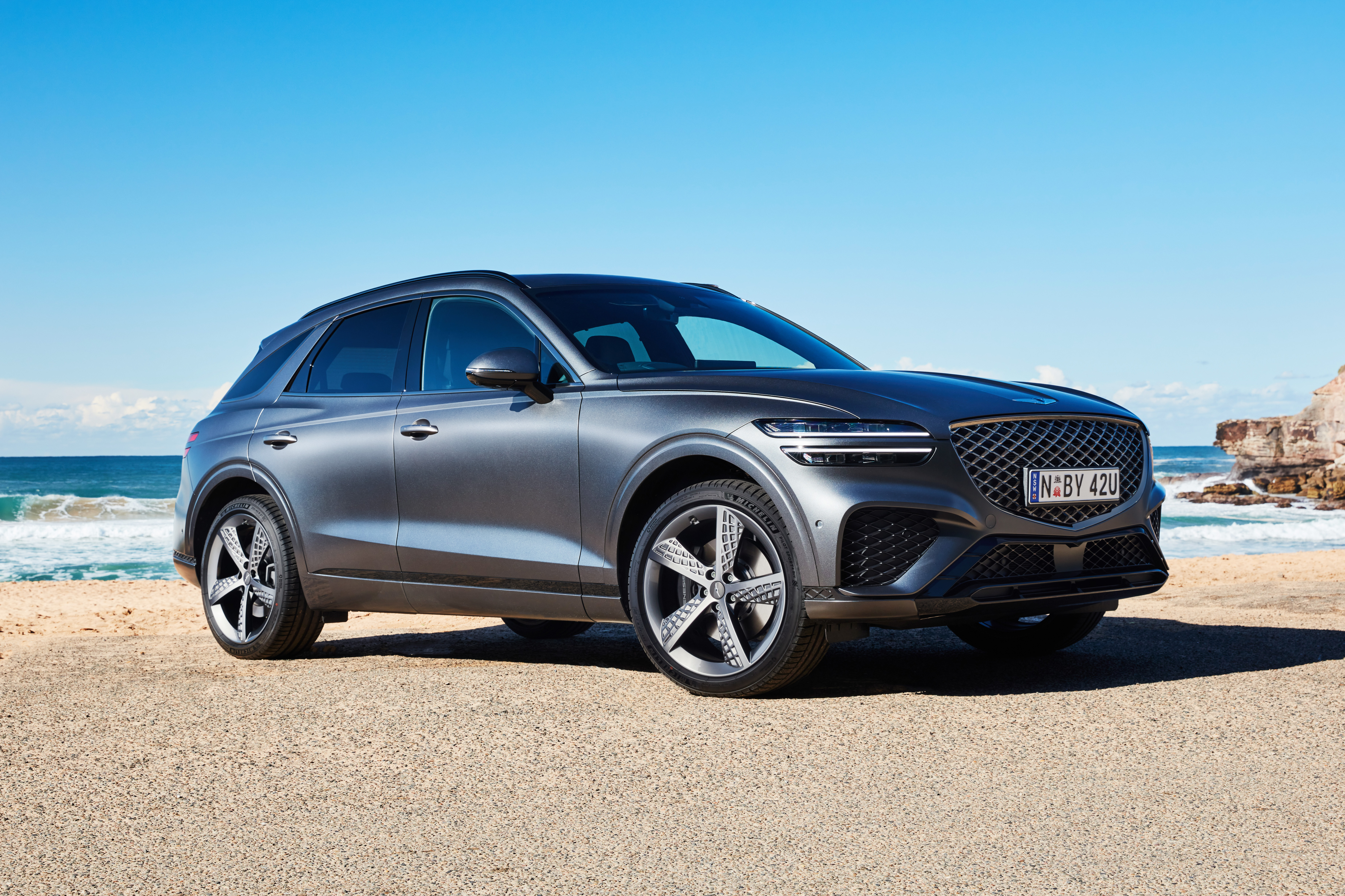 Grey Genesis GV70 SUV parked on a sunny beach HD Wallpaper