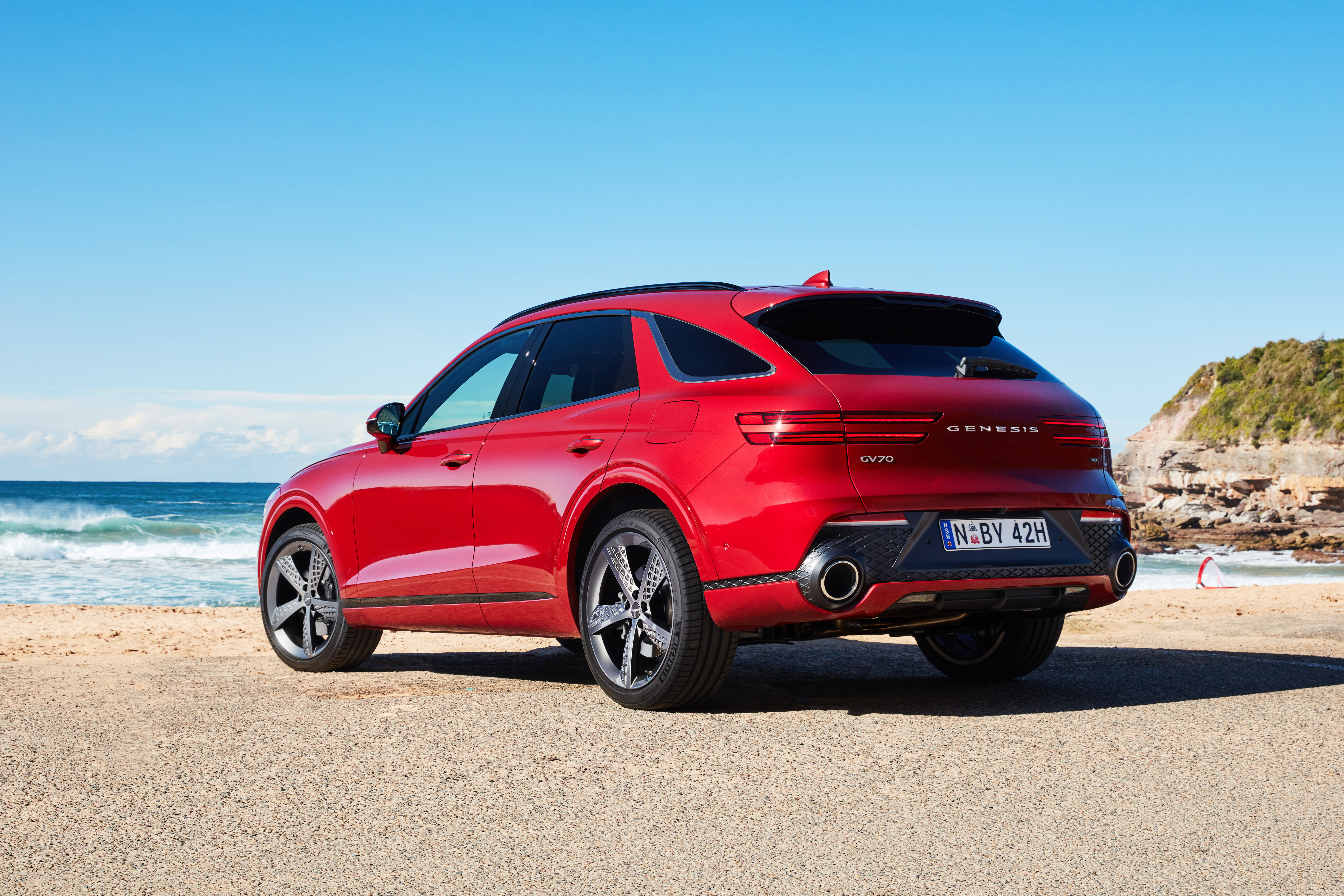 Red Genesis GV70 SUV parked on a sunny beach HD Wallpaper