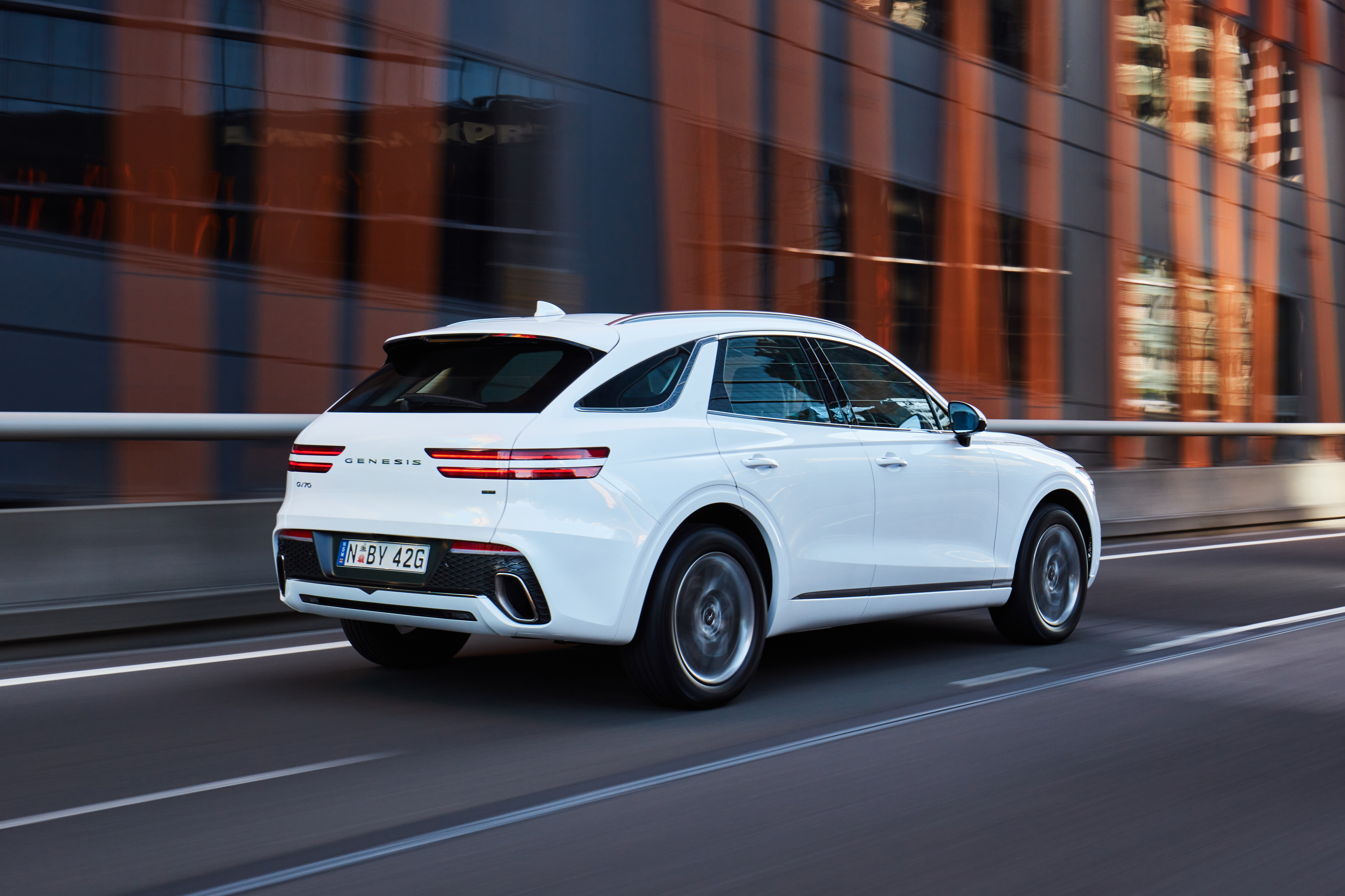 White Genesis GV70 2.5T SUV driving on a road HD Wallpaper