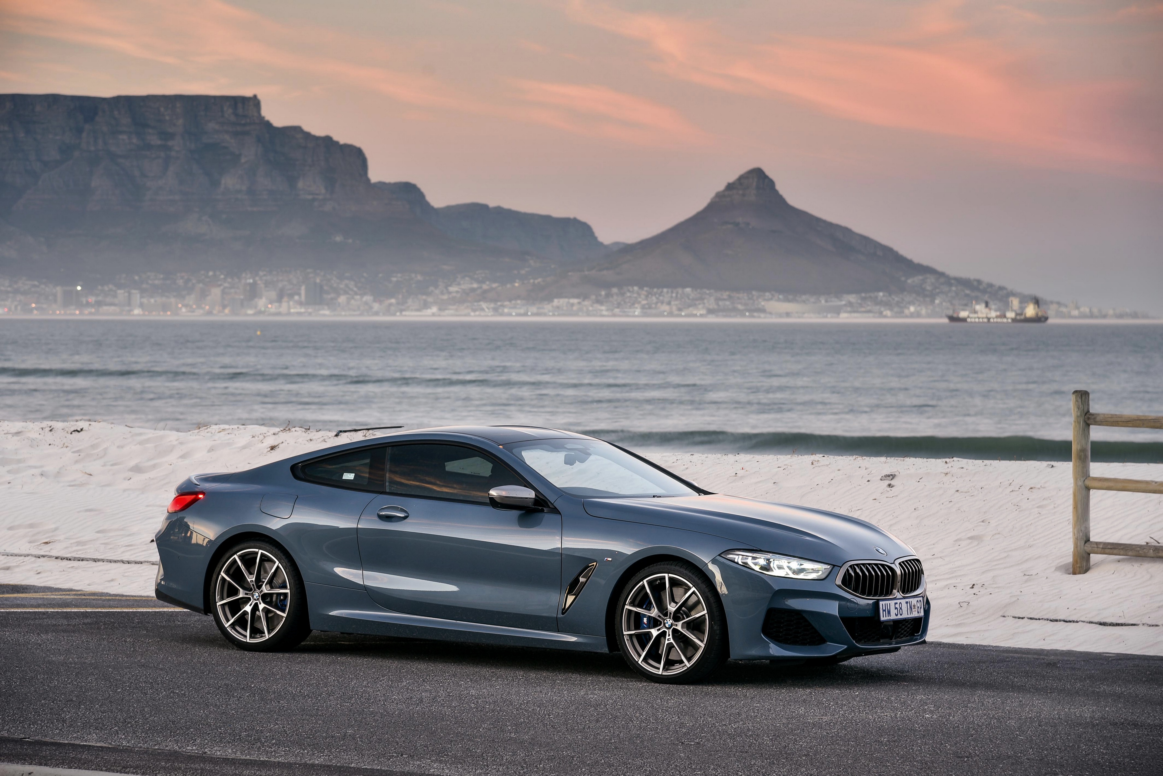 BMW M850i luxury car by the ocean and mountains at sunset HD Wallpaper