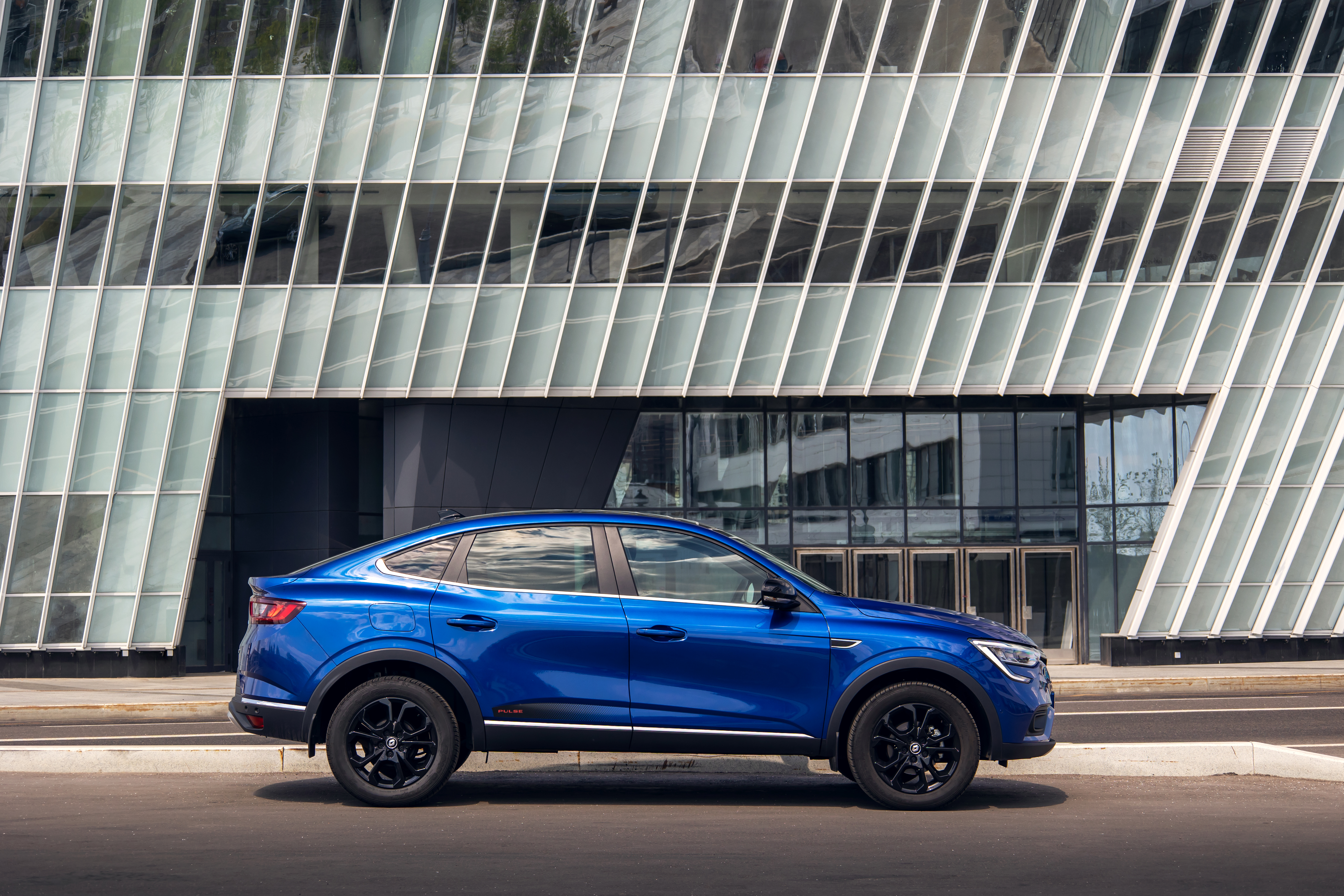 Renault Arkana "Pulse" SUV in front of a modern building HD Wallpaper