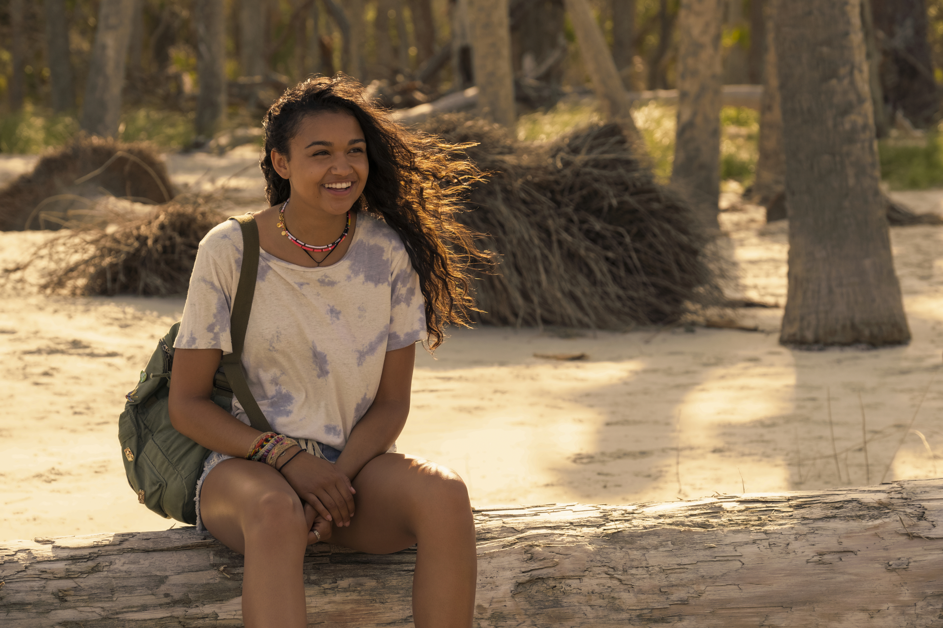 Madison Bailey smiling on a log at Outer Banks beach HD Wallpaper