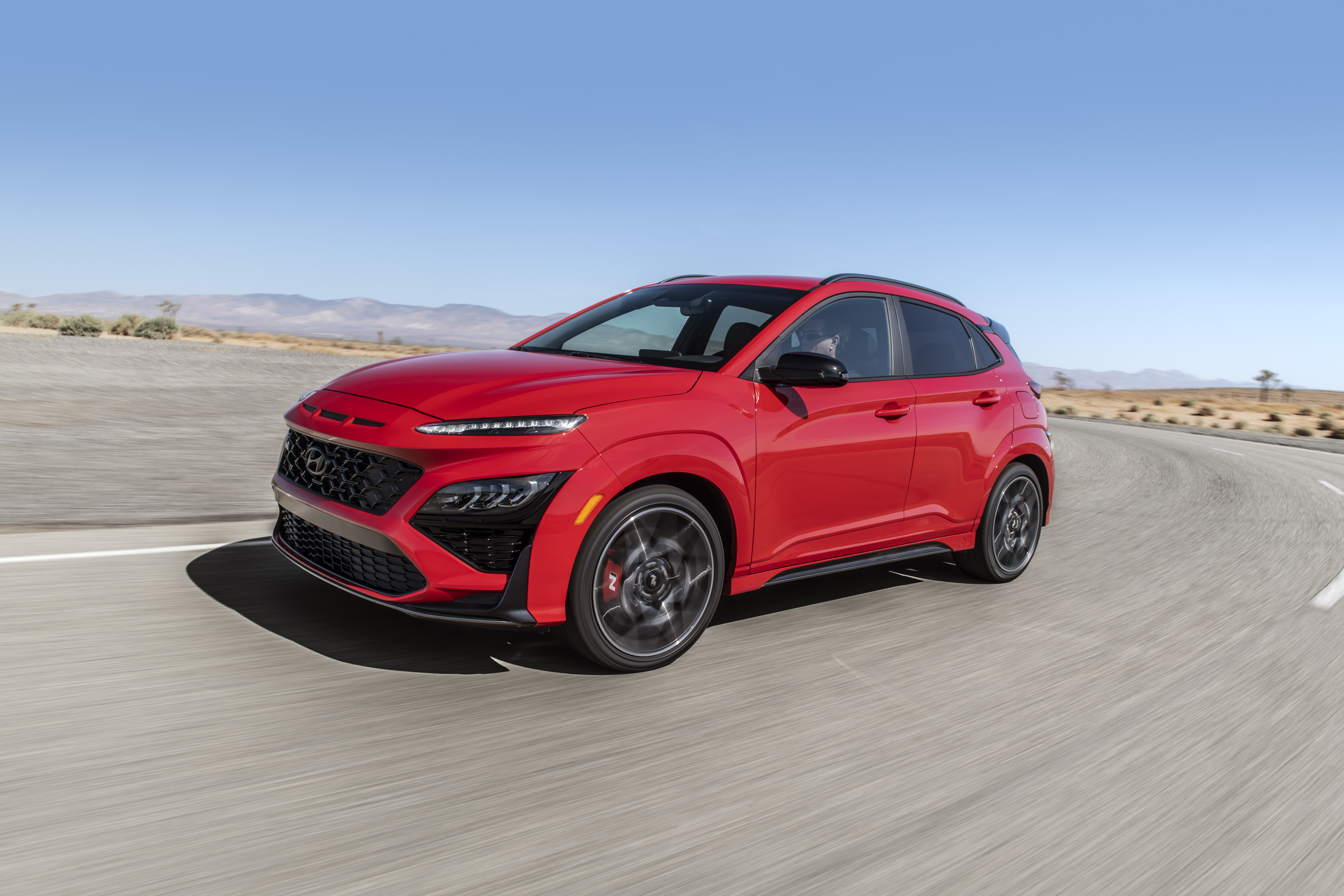 Red 2022 Hyundai Kona N SUV driving on desert road HD Wallpaper