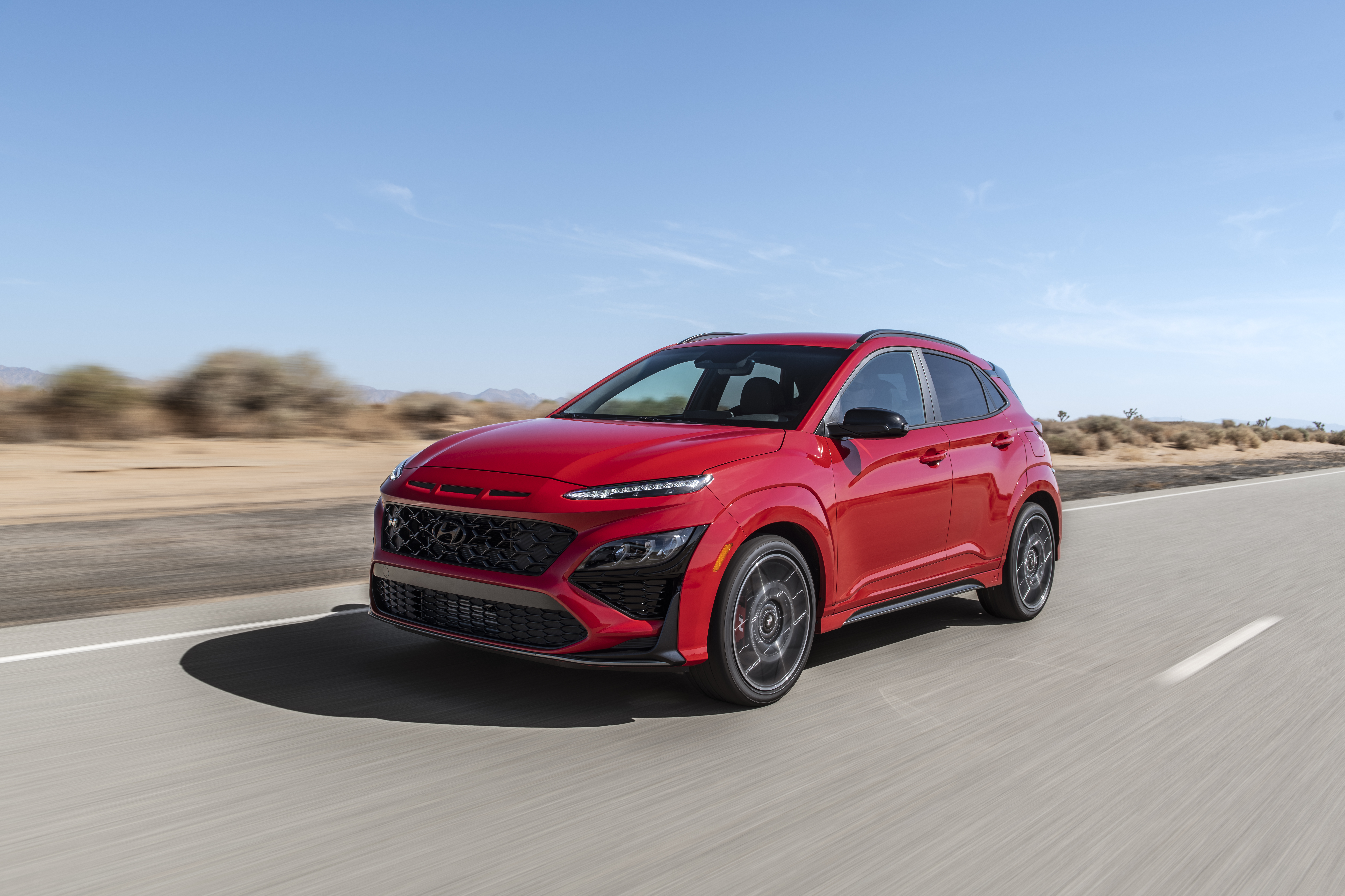Red 2022 Hyundai Kona N SUV driving on desert road HD Wallpaper