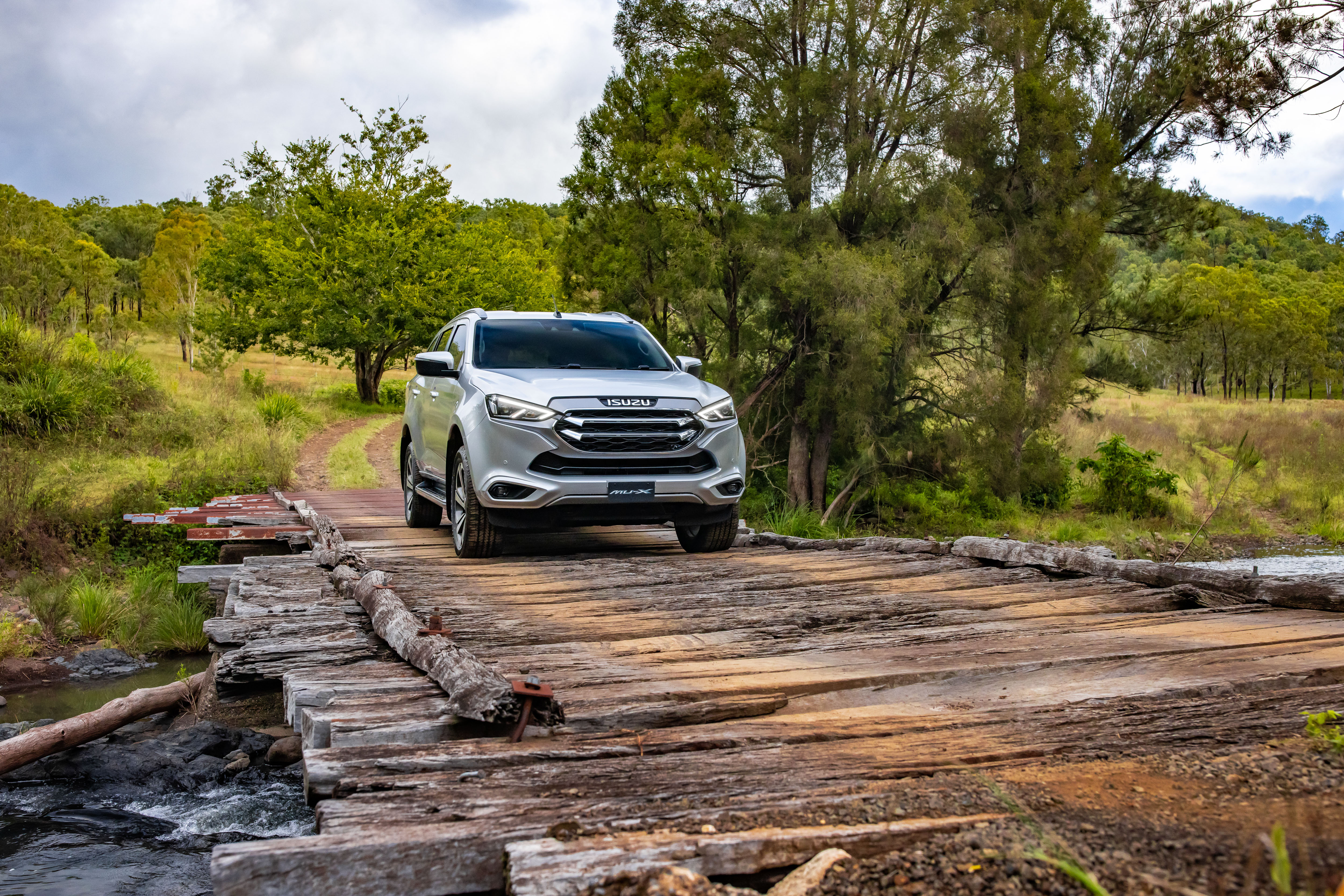 Isuzu MU-X SUV crossing a rustic wooden bridge HD Wallpaper