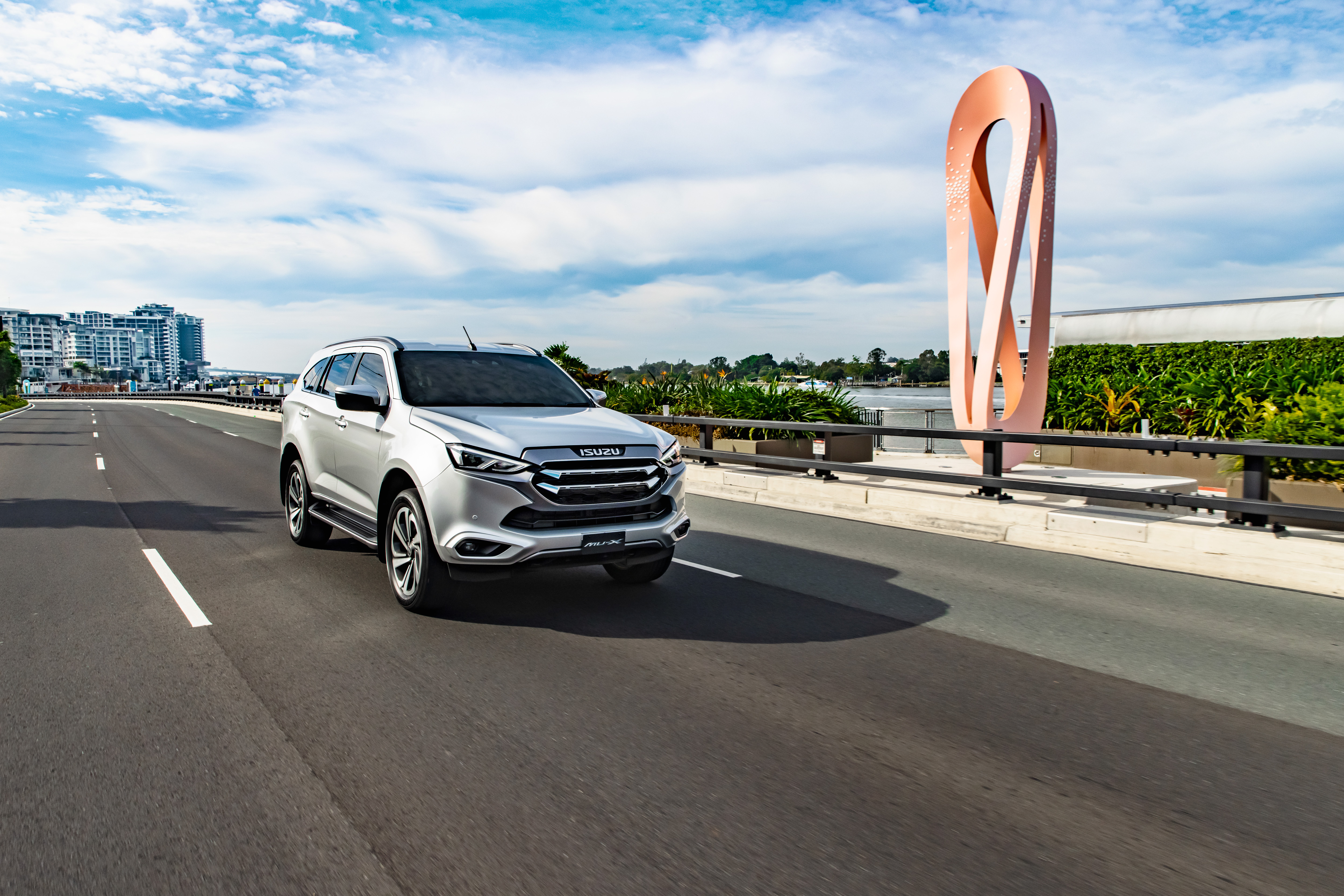 Isuzu MU-X SUV on road with unique sculpture HD Wallpaper
