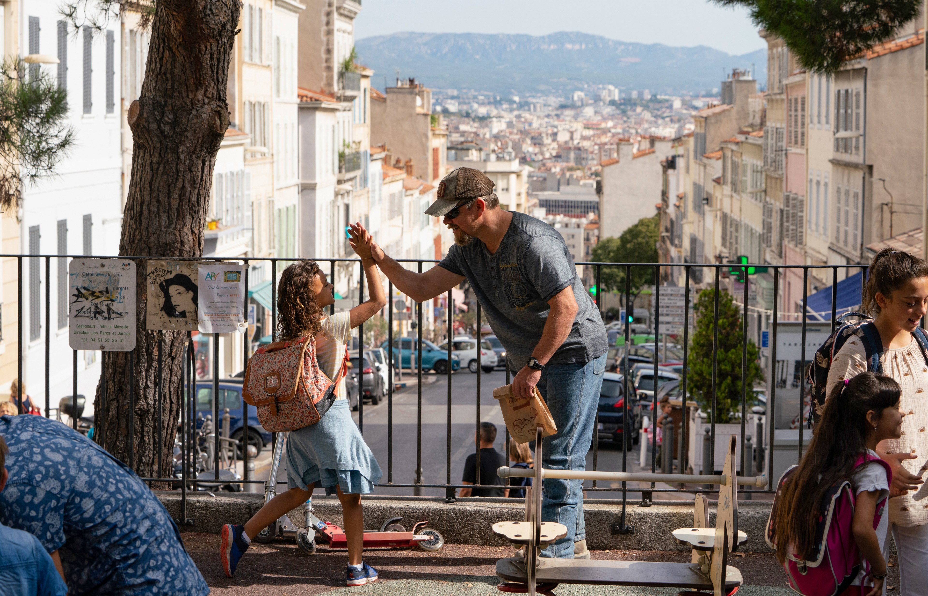 Man and girl high-fiving in city with mountain view HD Wallpaper