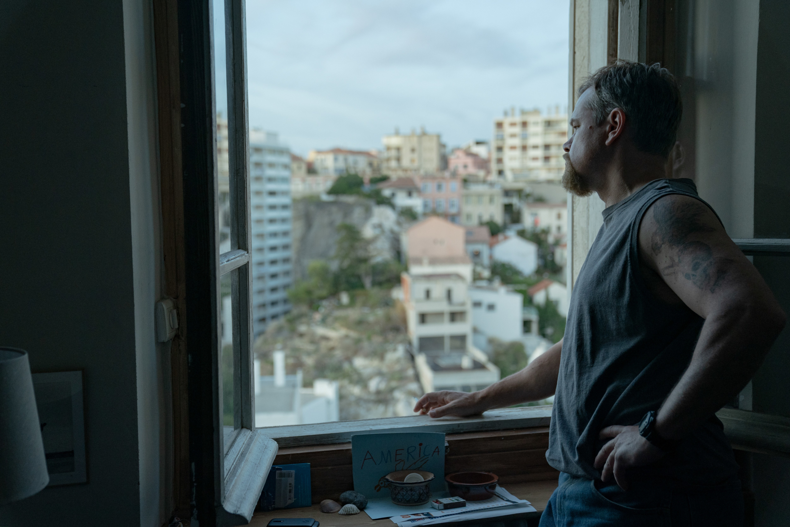 Matt Damon pensive at window overlooking city in Stillwater HD Wallpaper
