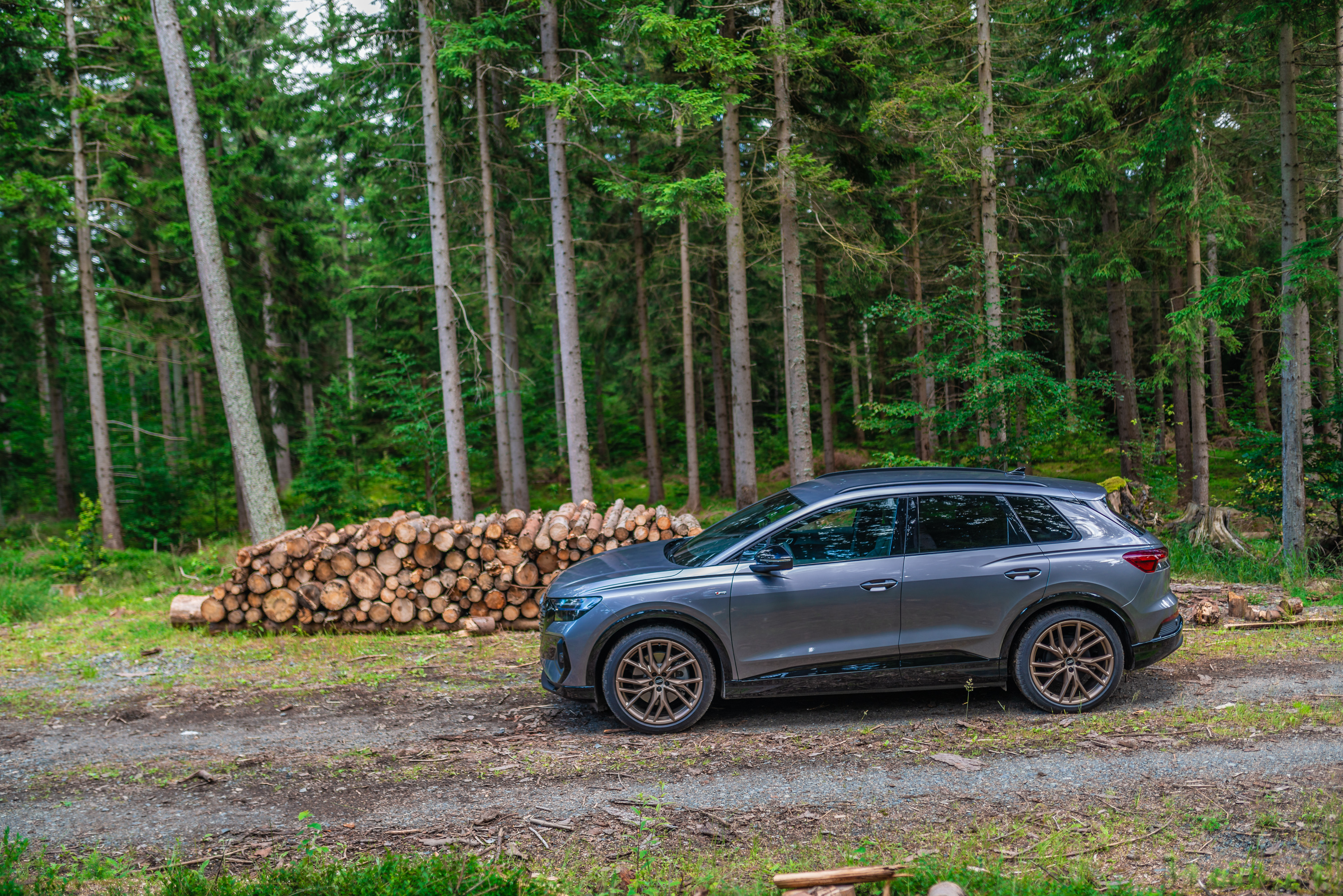 Audi Q4 e-tron SUV in a forest with logs HD Wallpaper