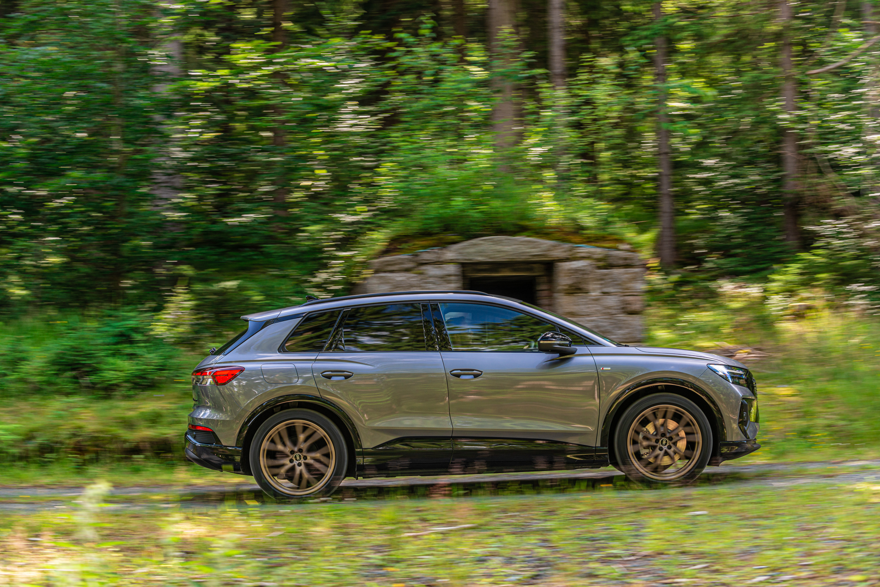 Audi Q4 e-tron SUV driving through a forest HD Wallpaper