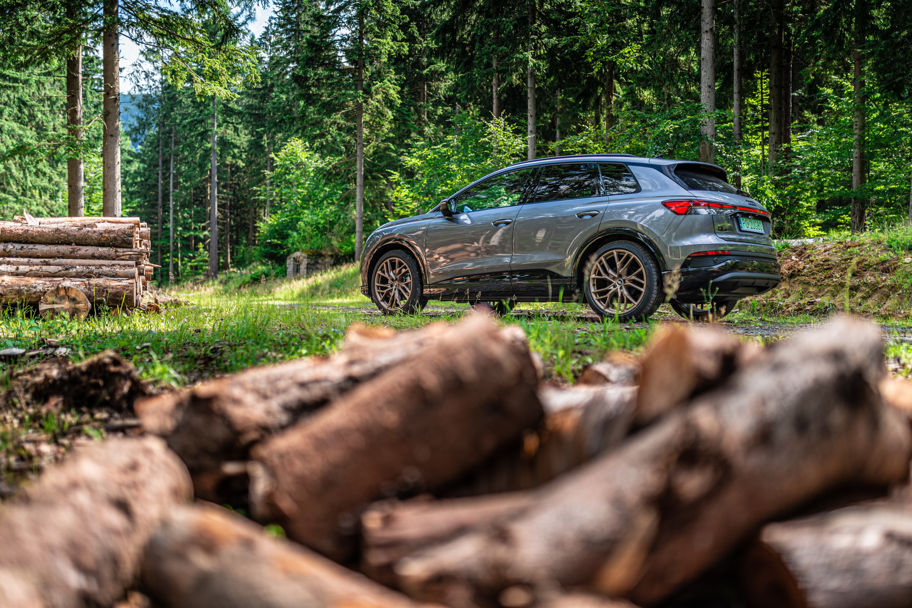 Audi Q4 e-tron SUV in forest with logs HD Wallpaper