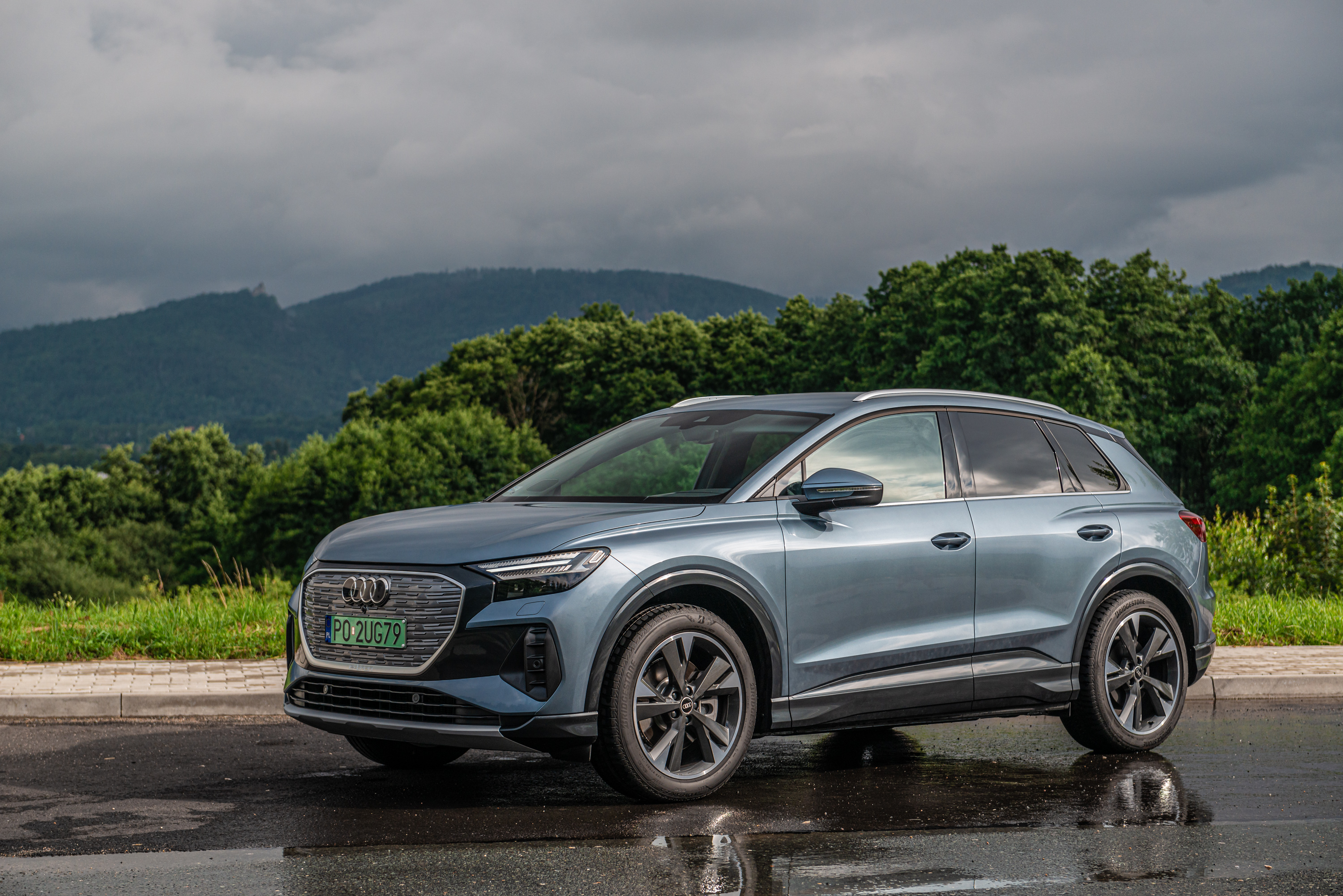 Audi Q4 E-tron electric SUV parked on a wet road HD Wallpaper