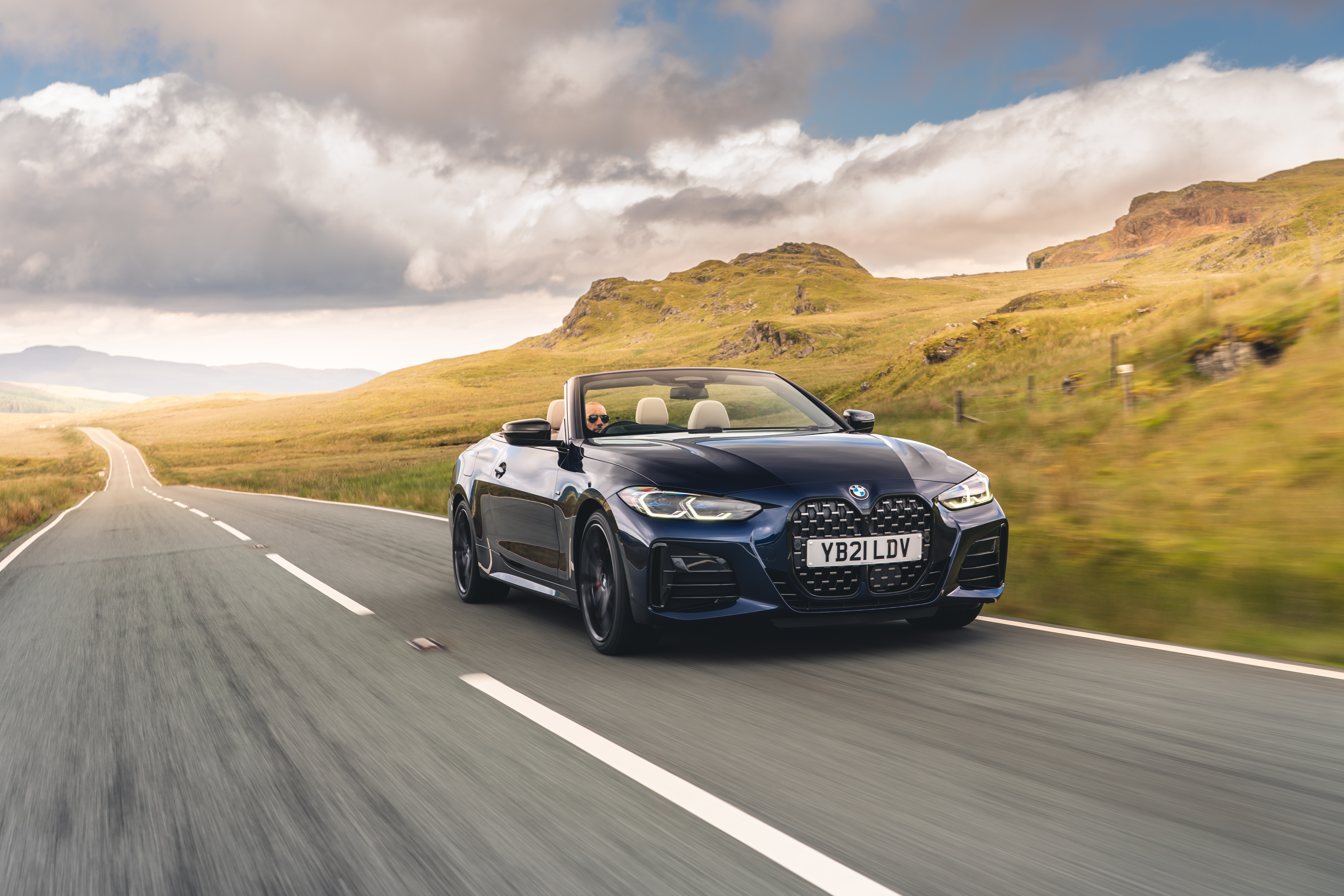 BMW M440i Cabriolet cruising through a hilly landscape HD Wallpaper
