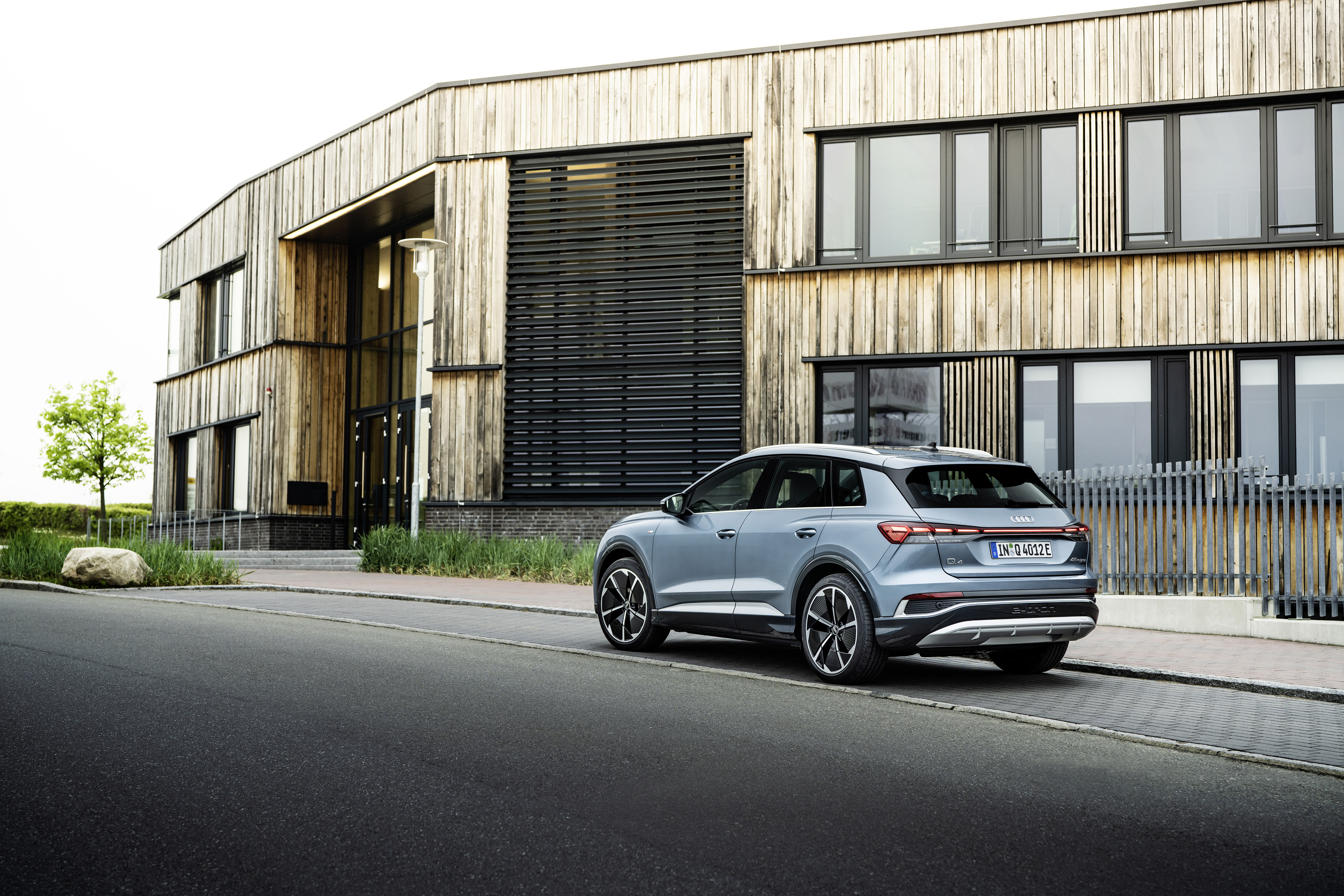 Blue Audi Q4 e-tron electric SUV at modern building. HD Wallpaper