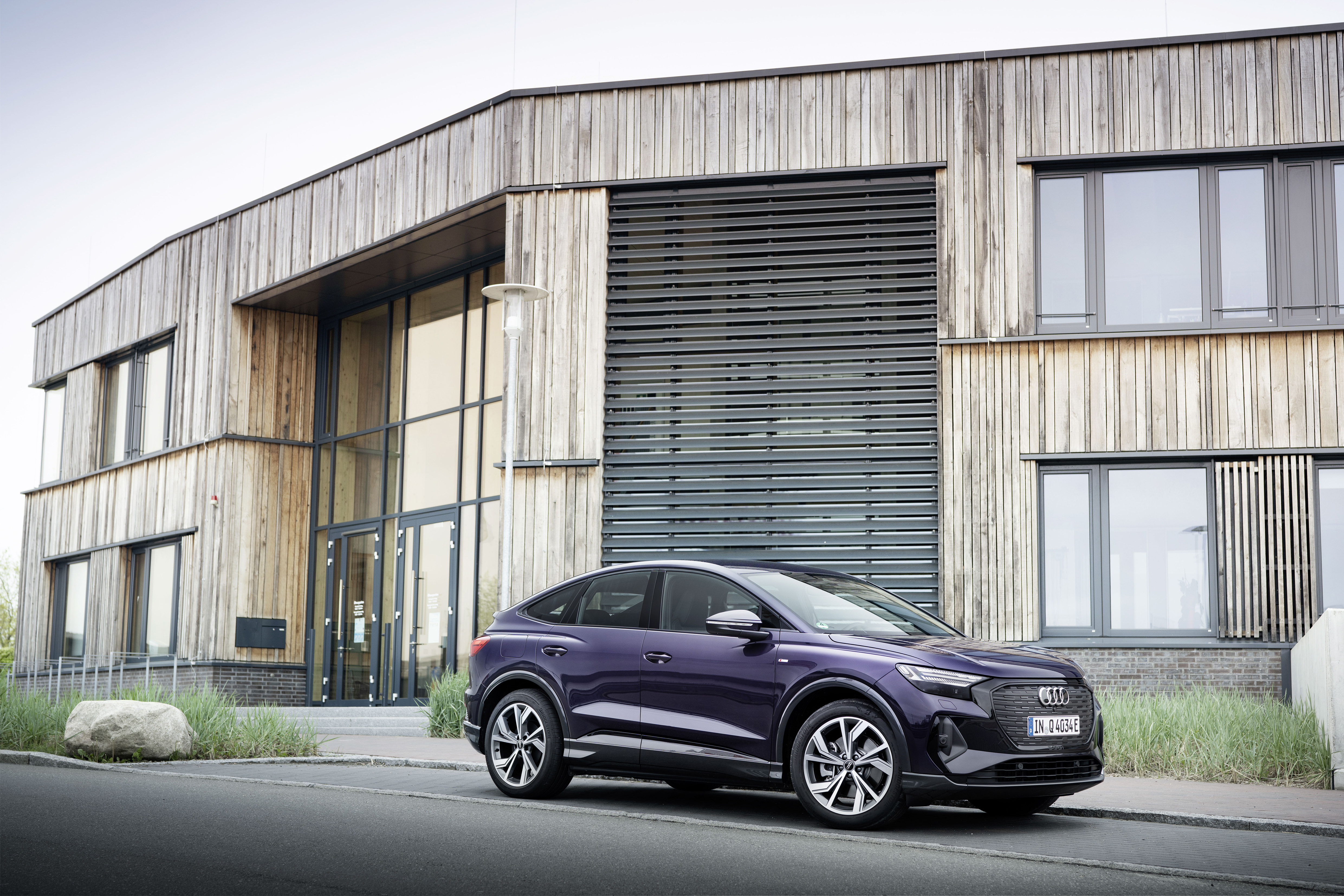 Purple Audi Q4 Sportback e-tron electric SUV by modern building HD Wallpaper
