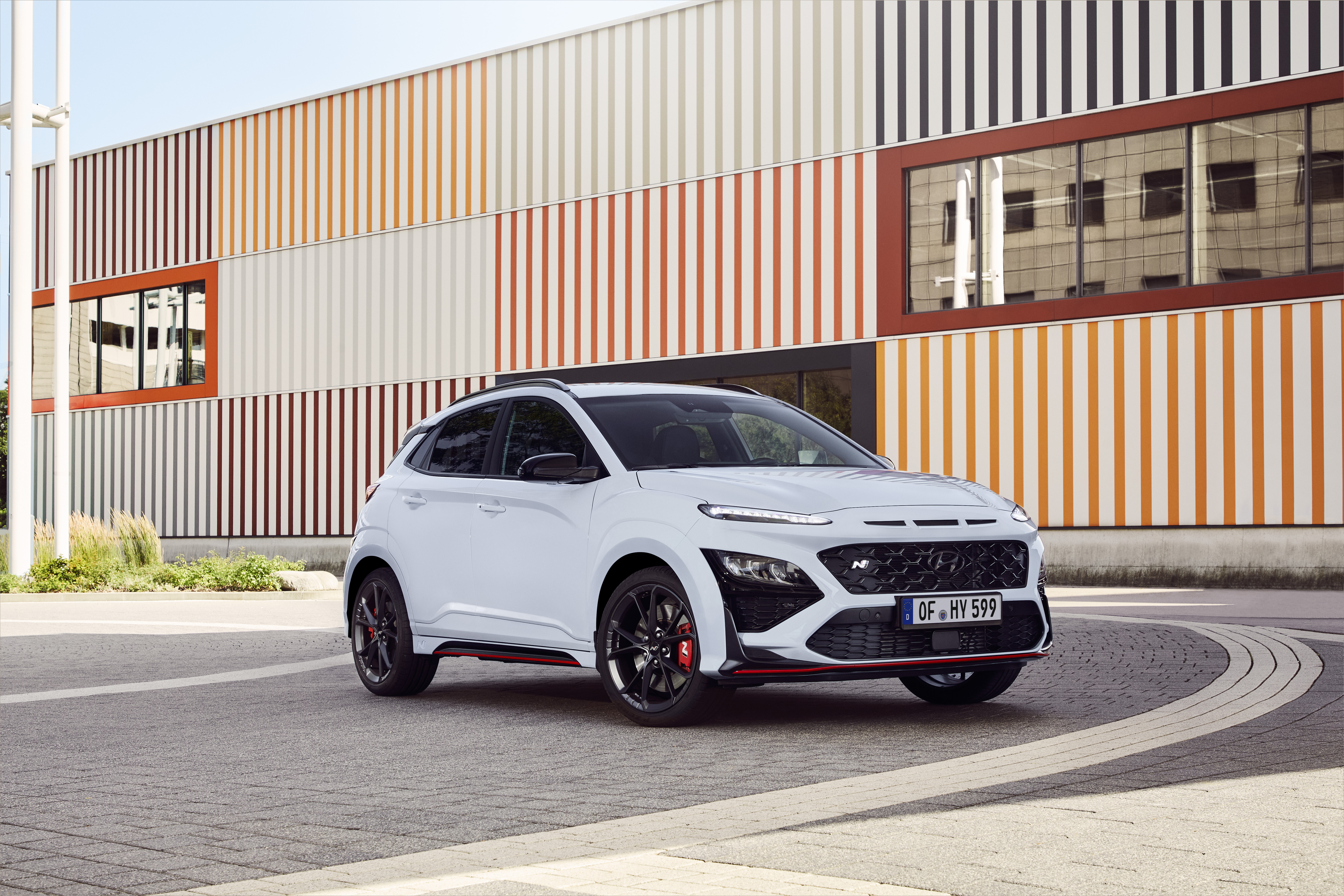 White Hyundai Kona N SUV parked by striped building HD Wallpaper