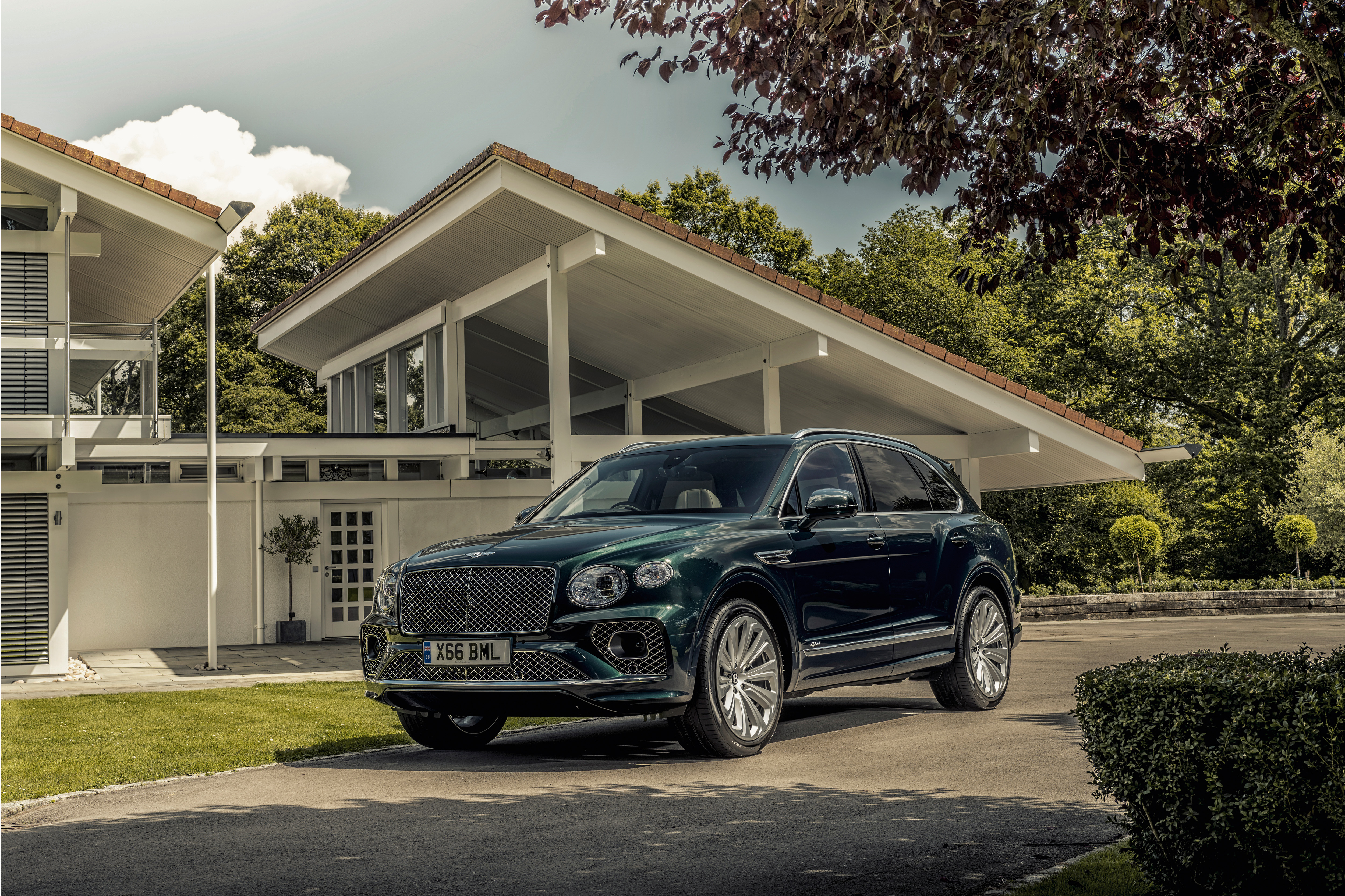 Dark green Bentley Bentayga Hybrid SUV at modern house HD Wallpaper
