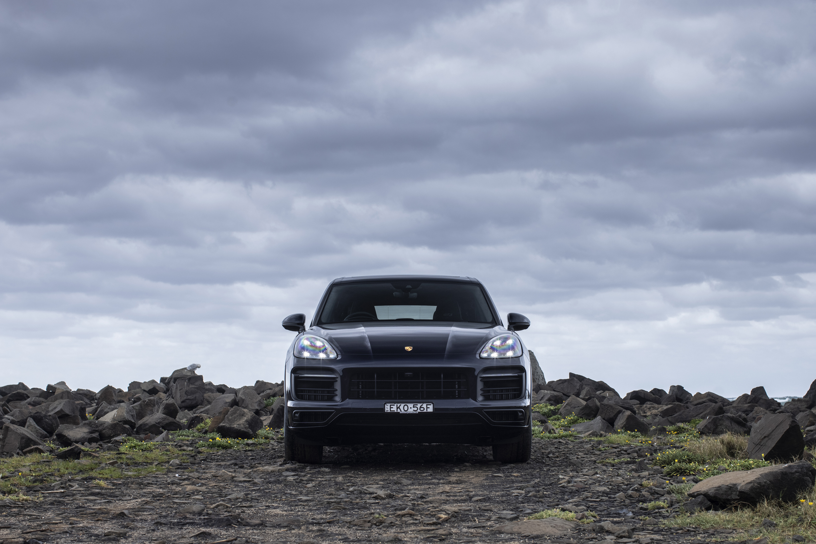 Black Porsche Cayenne GTS SUV on rocky ground HD Wallpaper