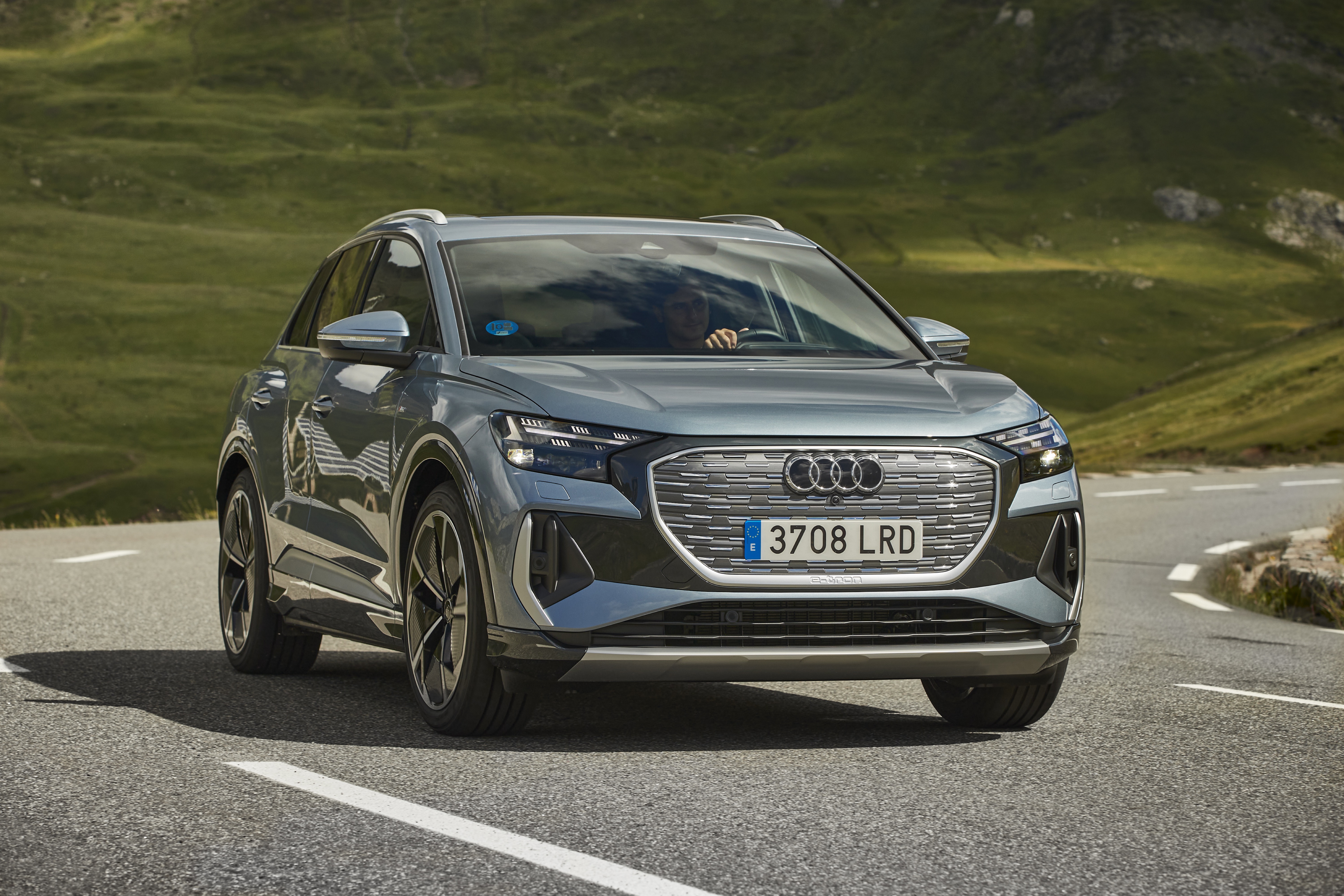 Audi Q4 e-tron electric SUV driving on a winding road HD Wallpaper
