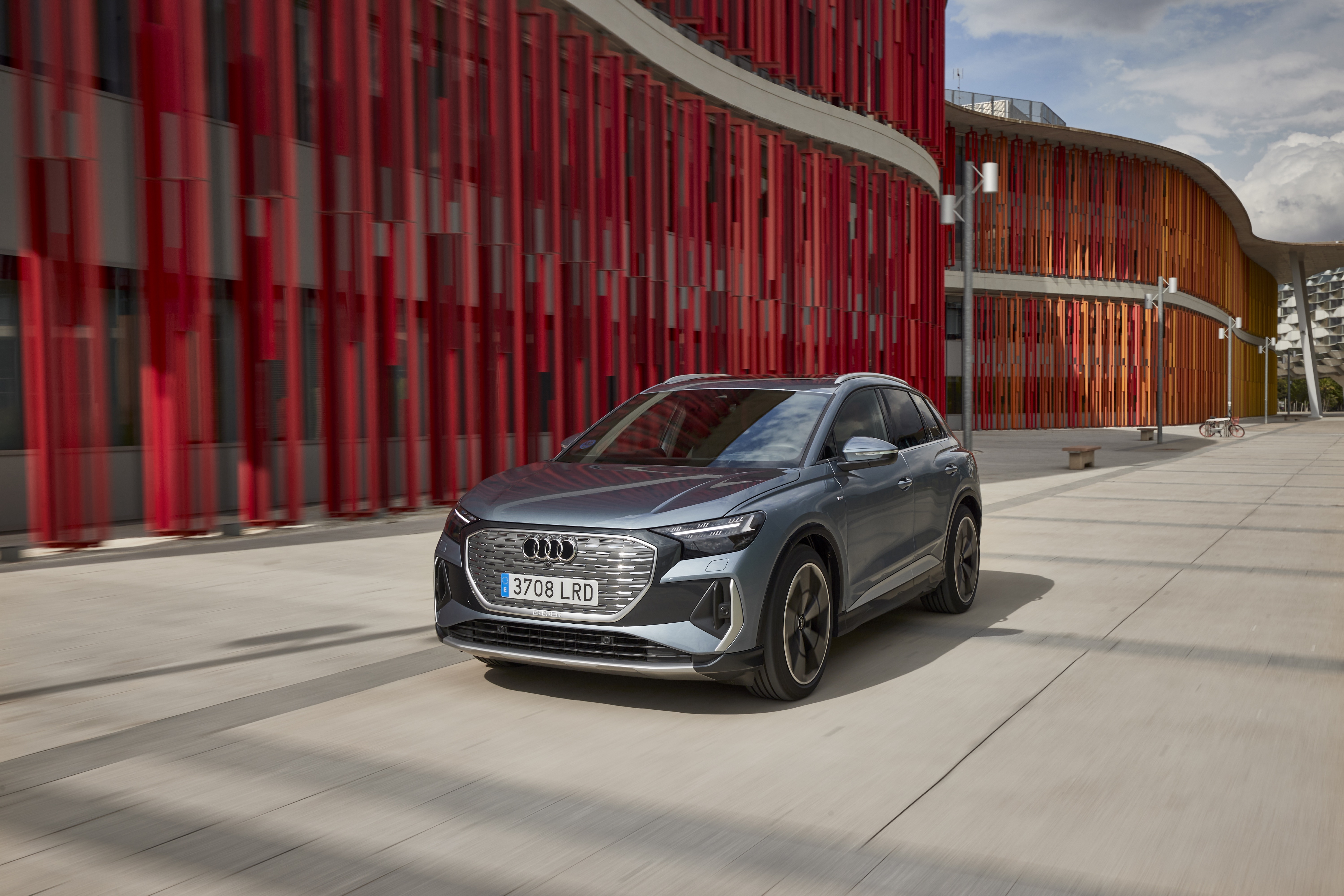 Audi Q4 e-tron electric SUV in modern urban setting HD Wallpaper