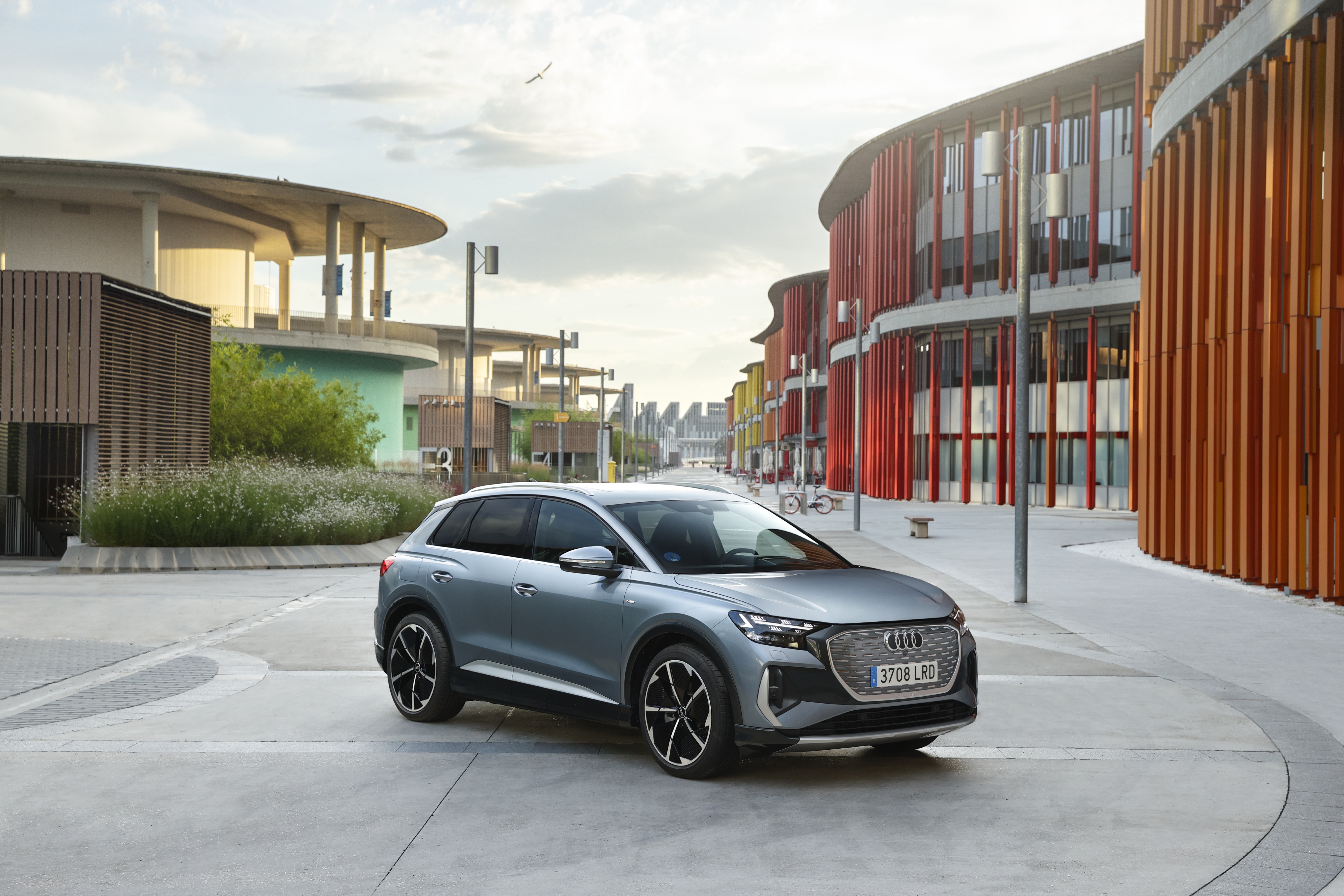 Audi Q4 e-tron S line electric SUV parked by colorful buildings HD Wallpaper
