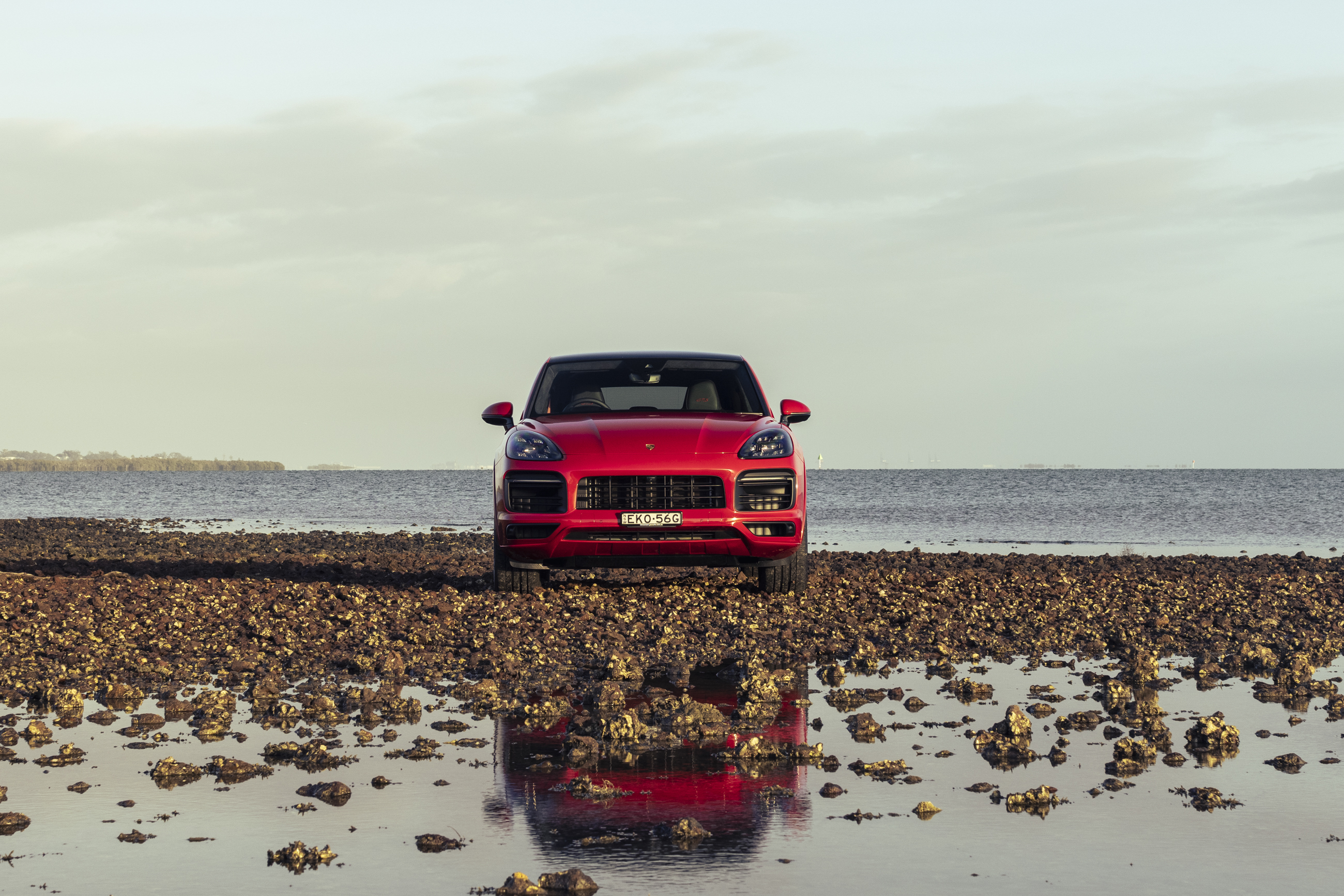 Red Porsche Cayenne GTS Coupé on a reflective beach HD Wallpaper
