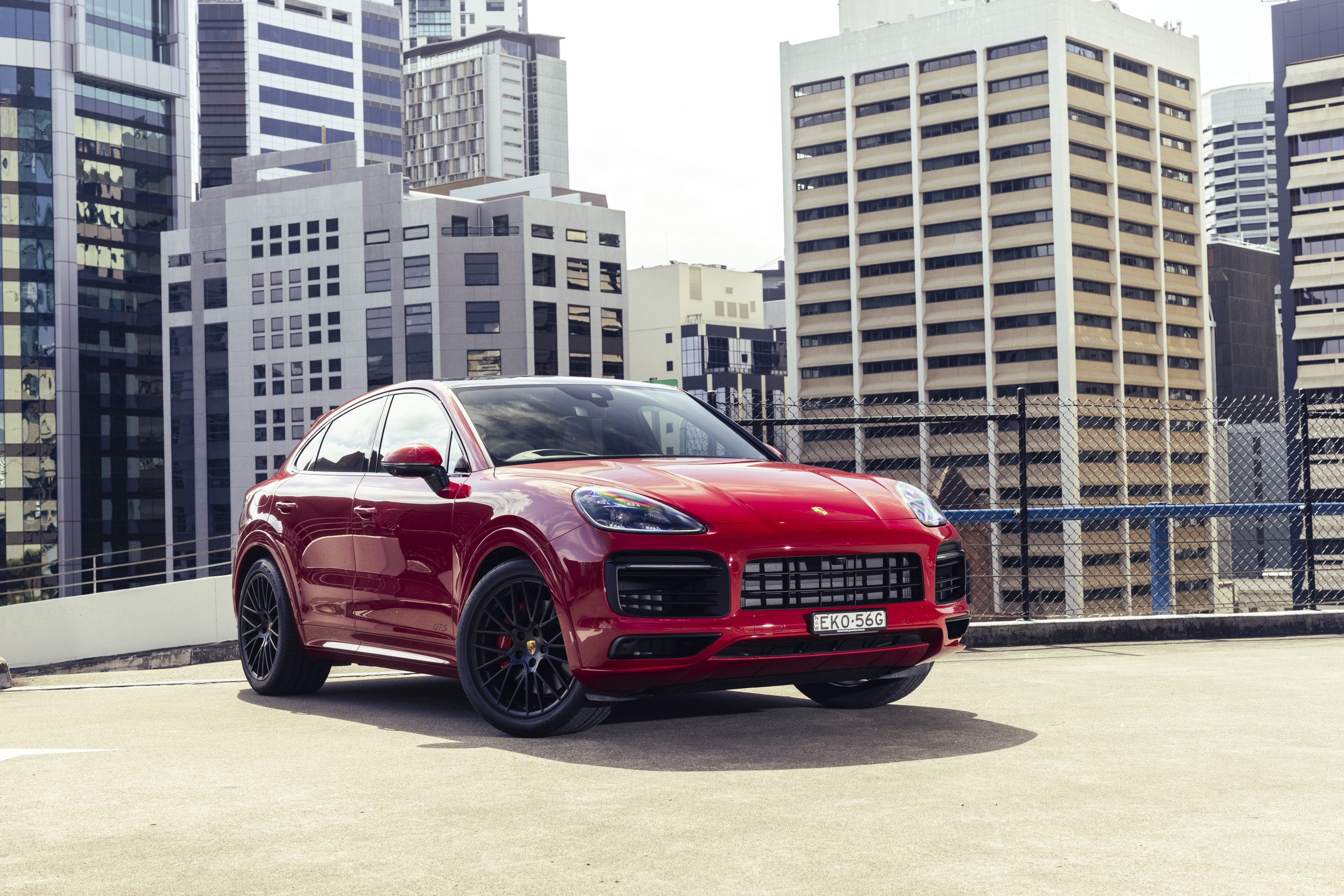 Red Porsche Cayenne GTS Coupé parked on a city rooftop HD Wallpaper