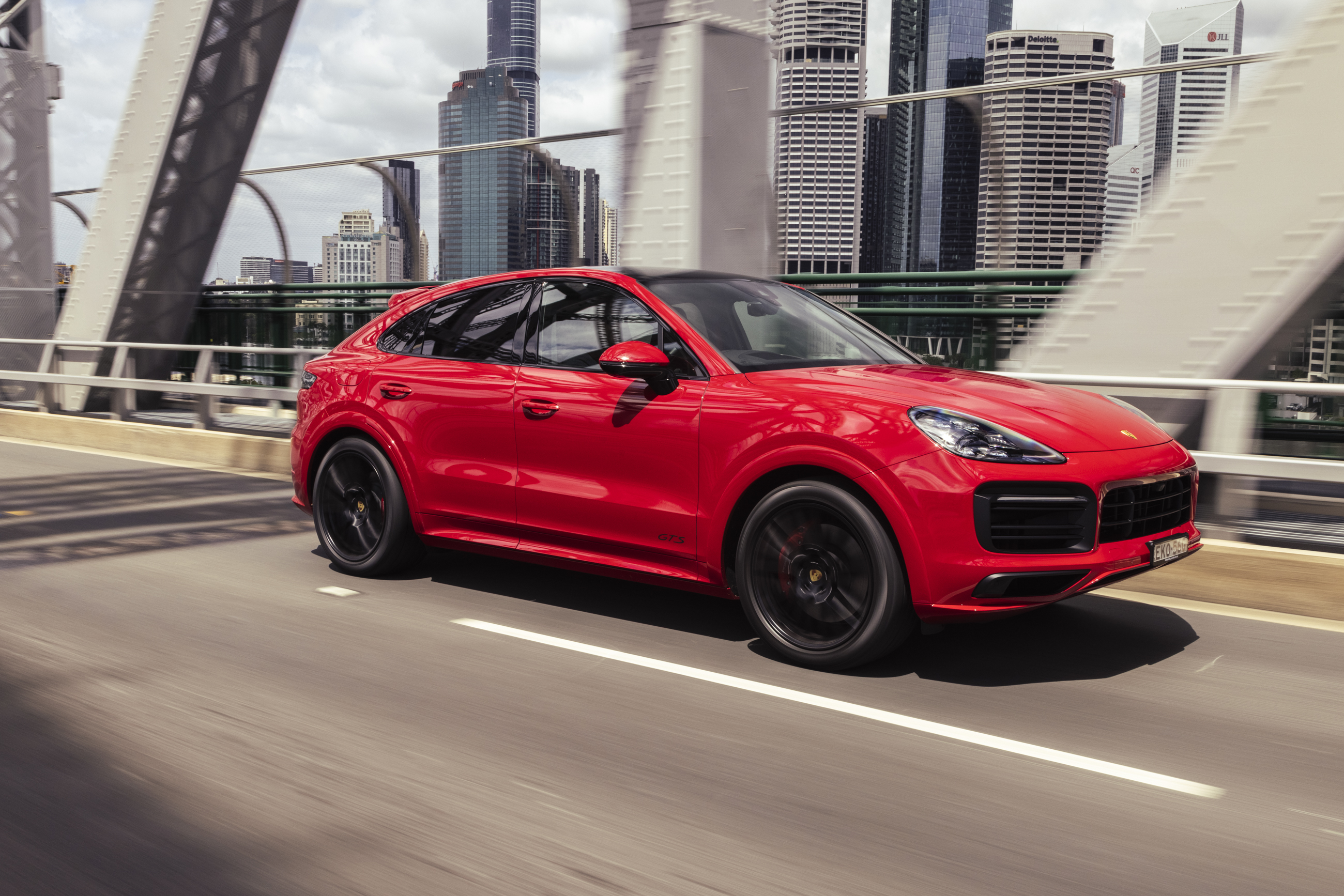Red Porsche Cayenne GTS Coupé driving on city bridge HD Wallpaper