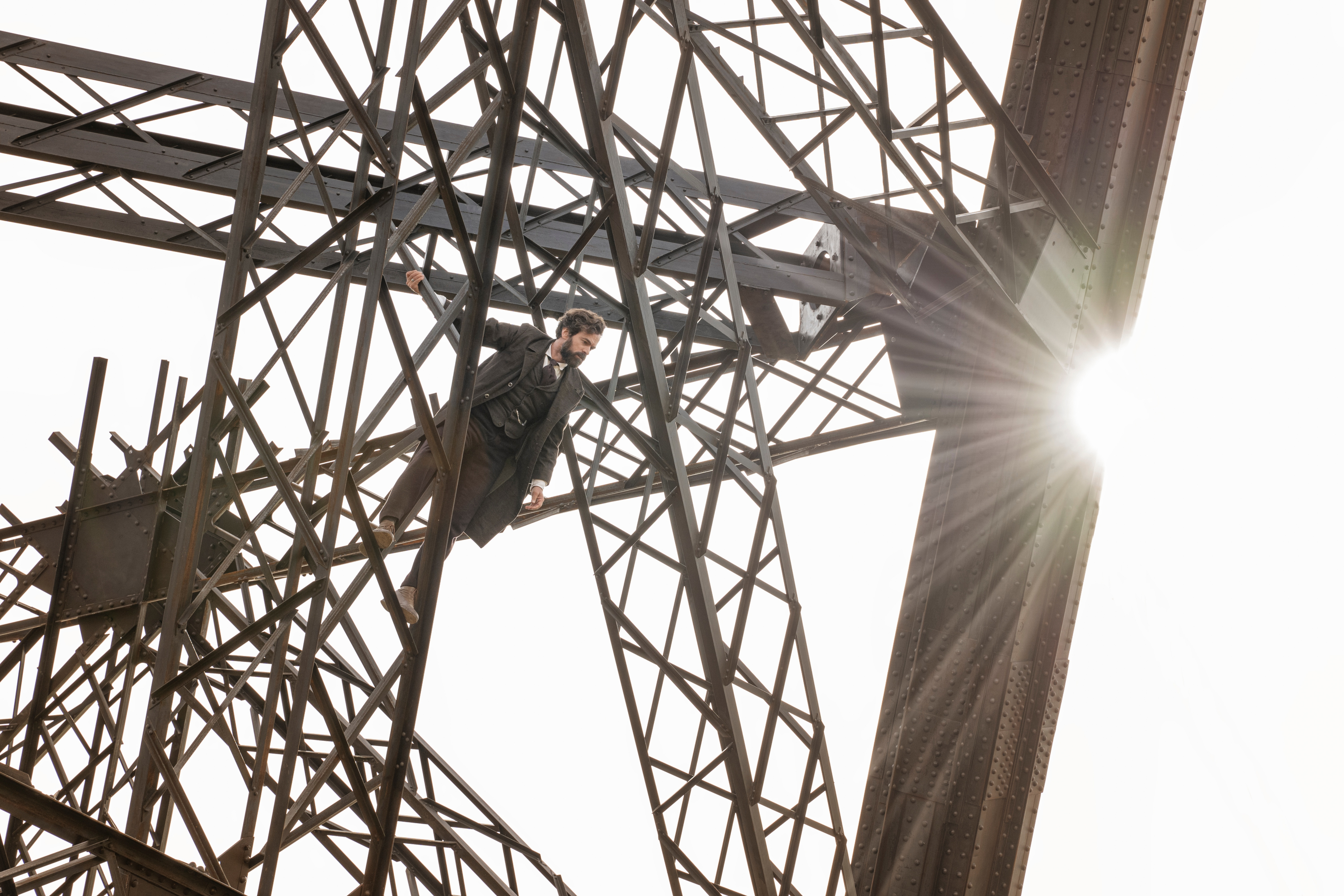 Romain Duris hanging from Eiffel Tower HD Wallpaper