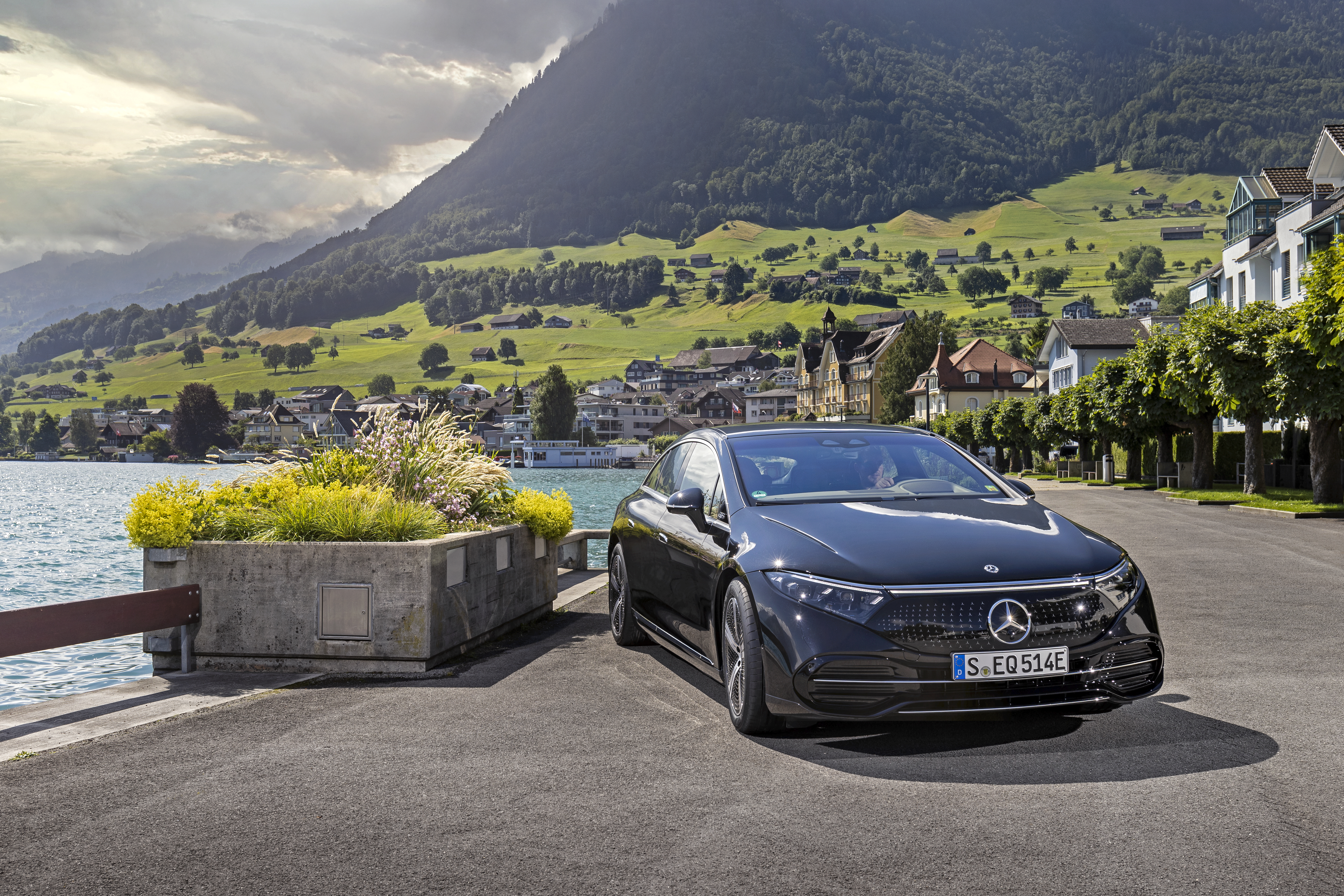 Black Mercedes-Benz EQS electric car in a scenic mountain village HD Wallpaper