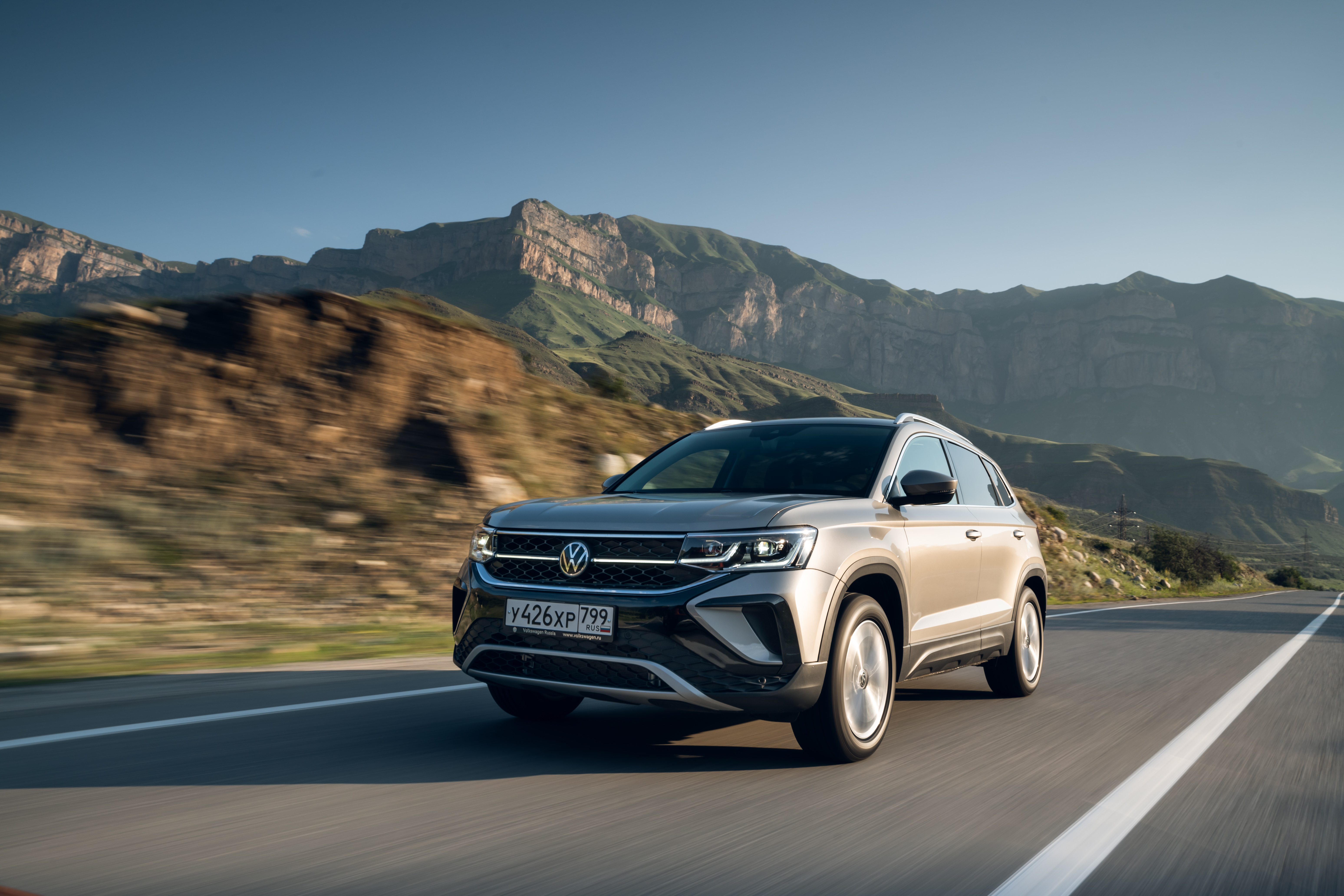 Grey 2021 Volkswagen Taos 4MOTION SUV driving on mountain road HD Wallpaper