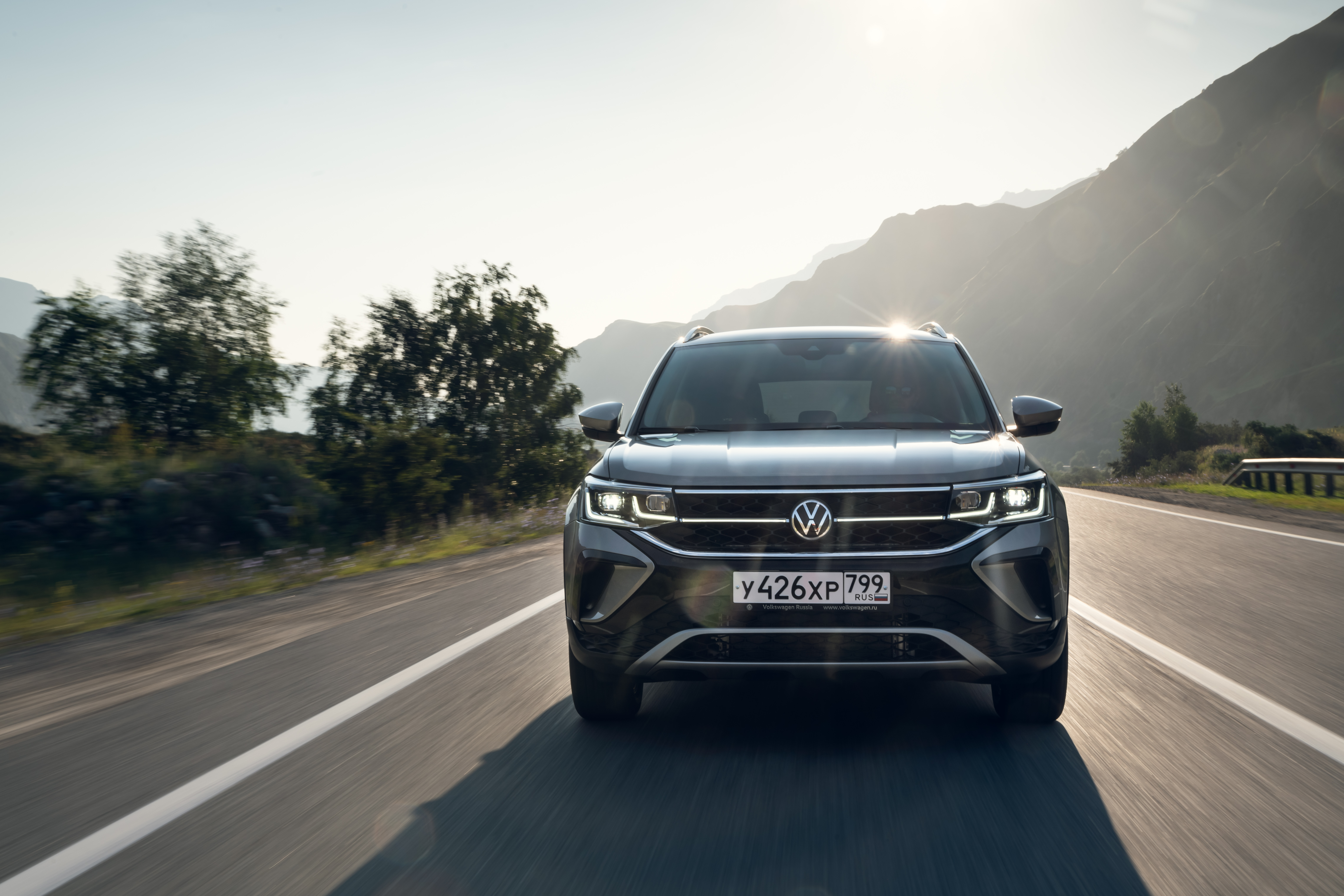 Volkswagen Taos SUV driving on a sunny mountain road HD Wallpaper
