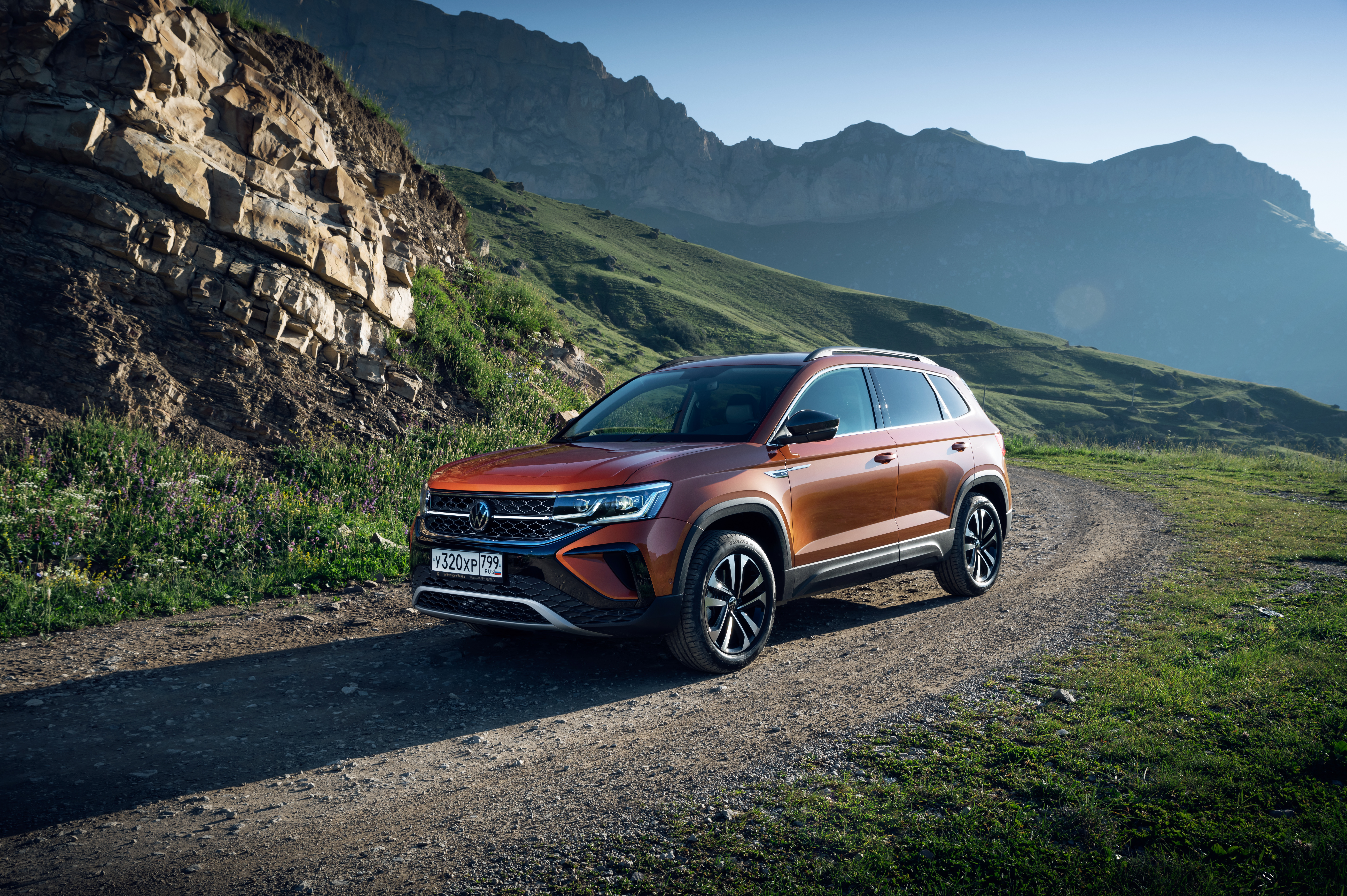 2021 Orange Volkswagen Taos SUV in mountainous landscape HD Wallpaper
