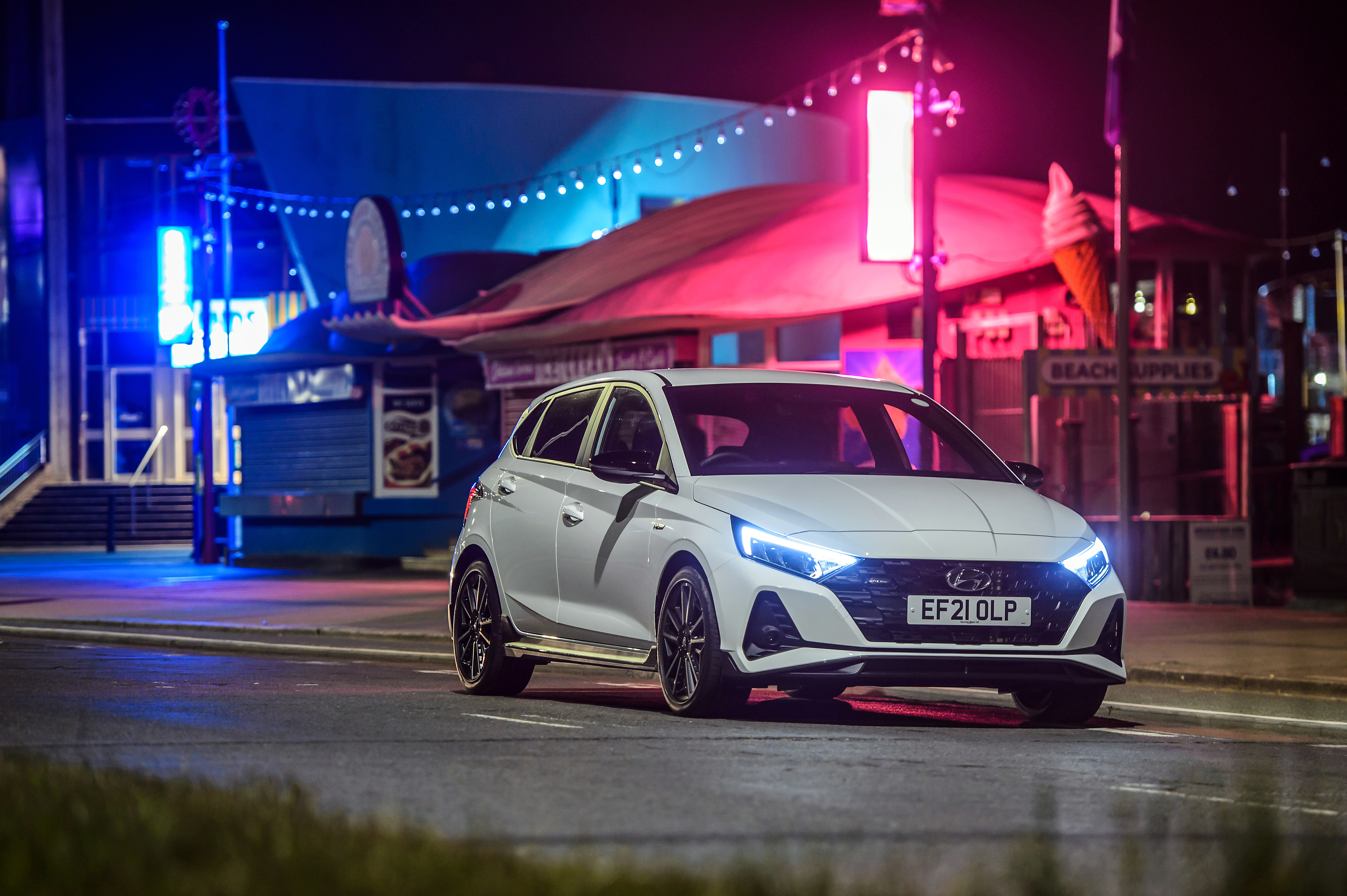 White Hyundai i20 N Line under colorful neon lights HD Wallpaper