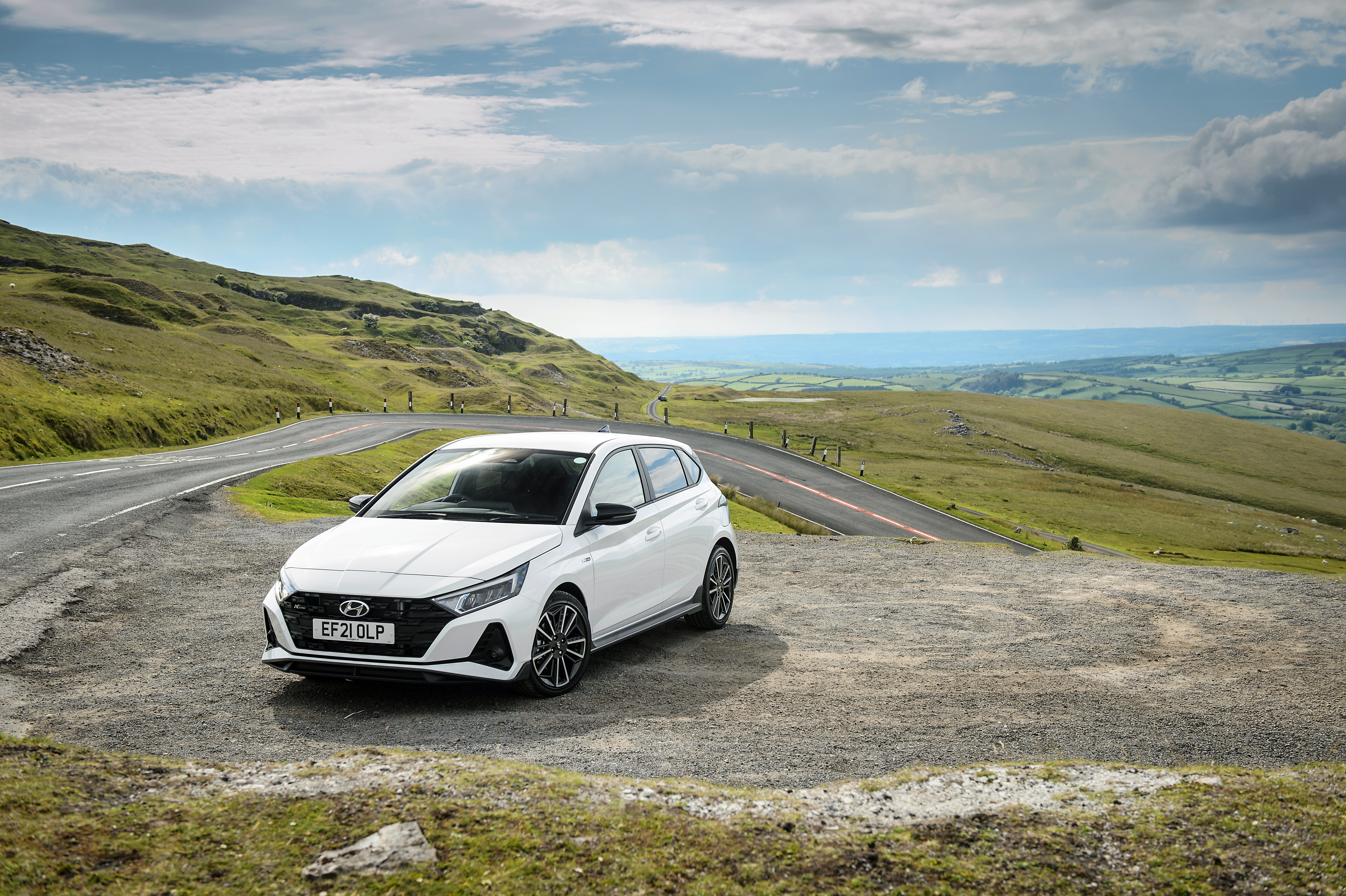 White Hyundai i20 N Line on a scenic mountain road HD Wallpaper