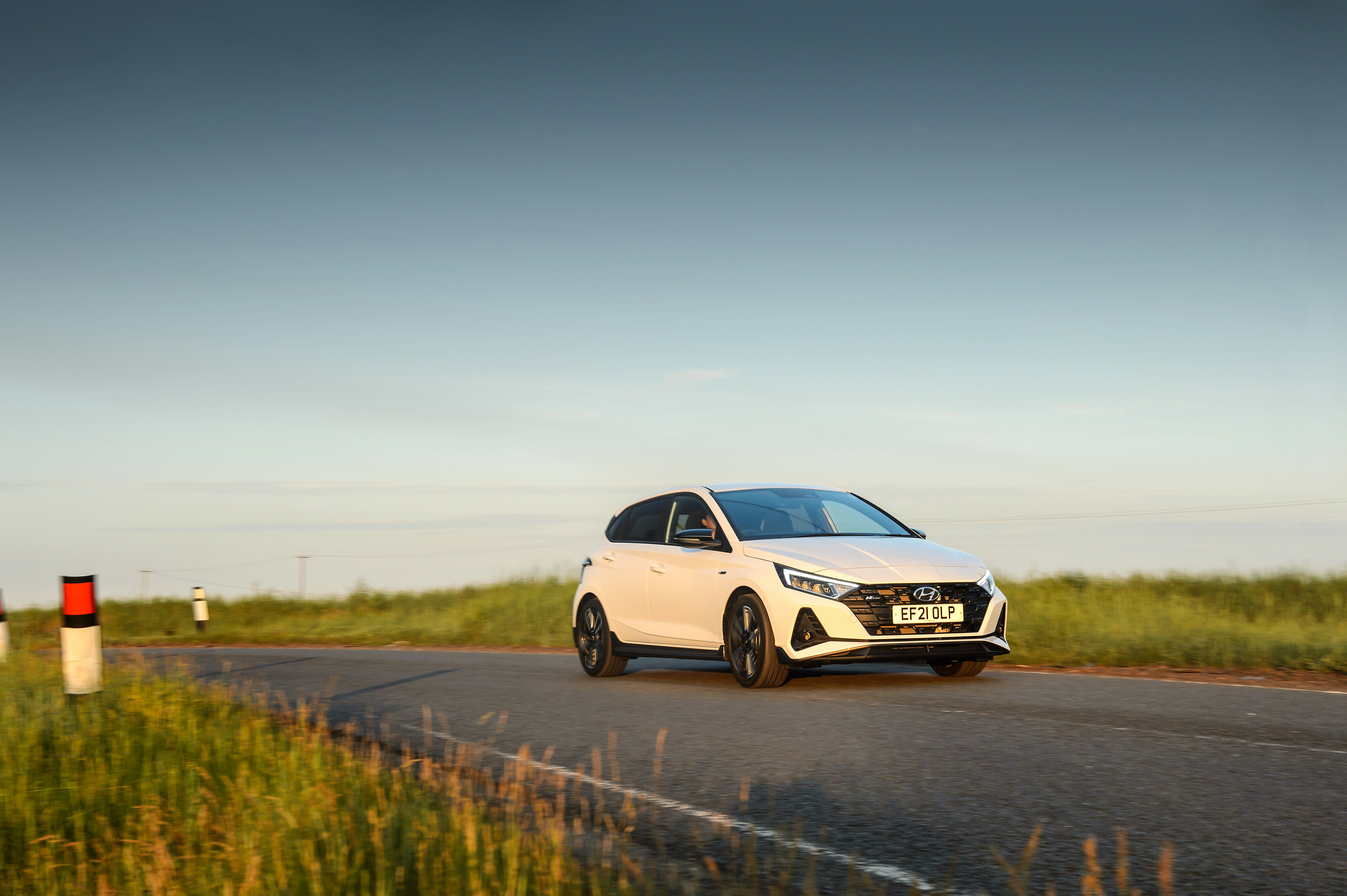 White Hyundai i20 N Line driving on a country road HD Wallpaper