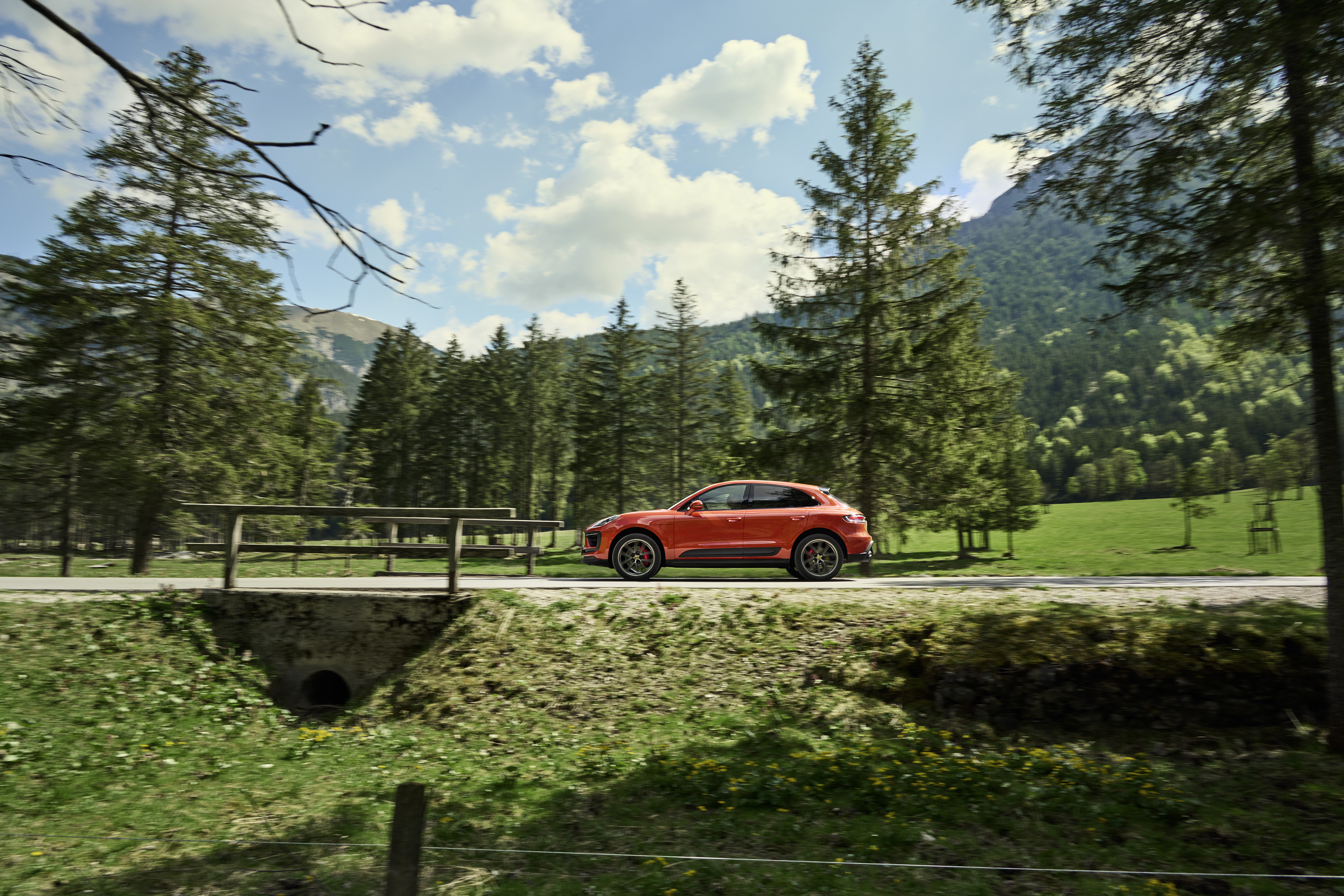 Red Porsche Macan SUV on a scenic mountain road HD Wallpaper