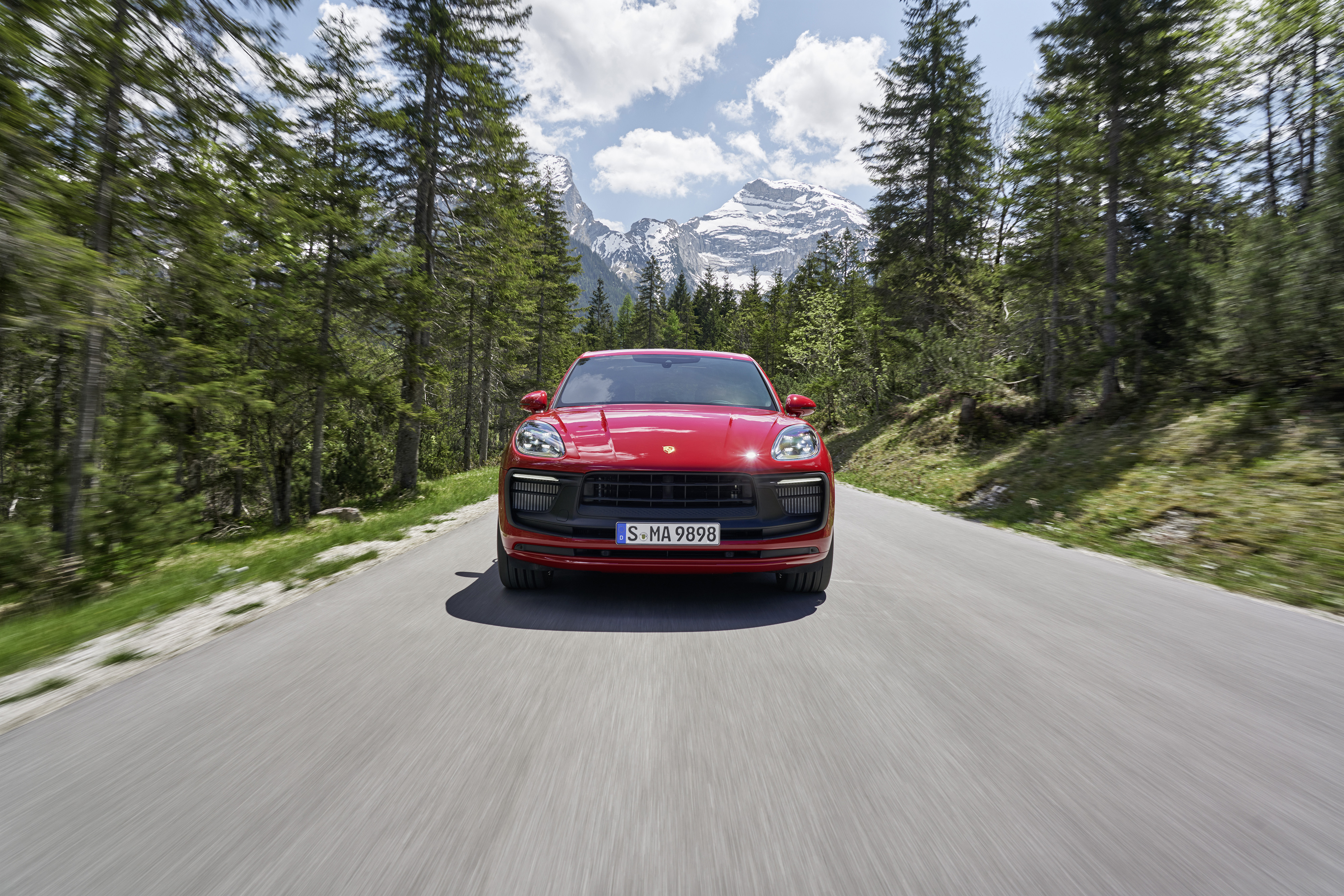 Red Porsche Macan GTS driving on a scenic mountain road HD Wallpaper