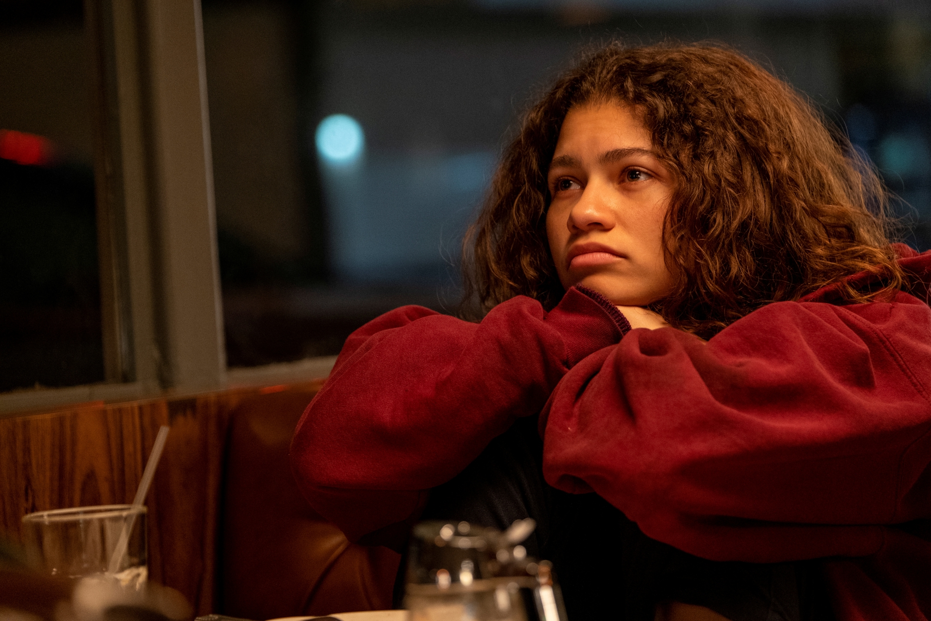 Zendaya looking pensive in a red hoodie at night HD Wallpaper