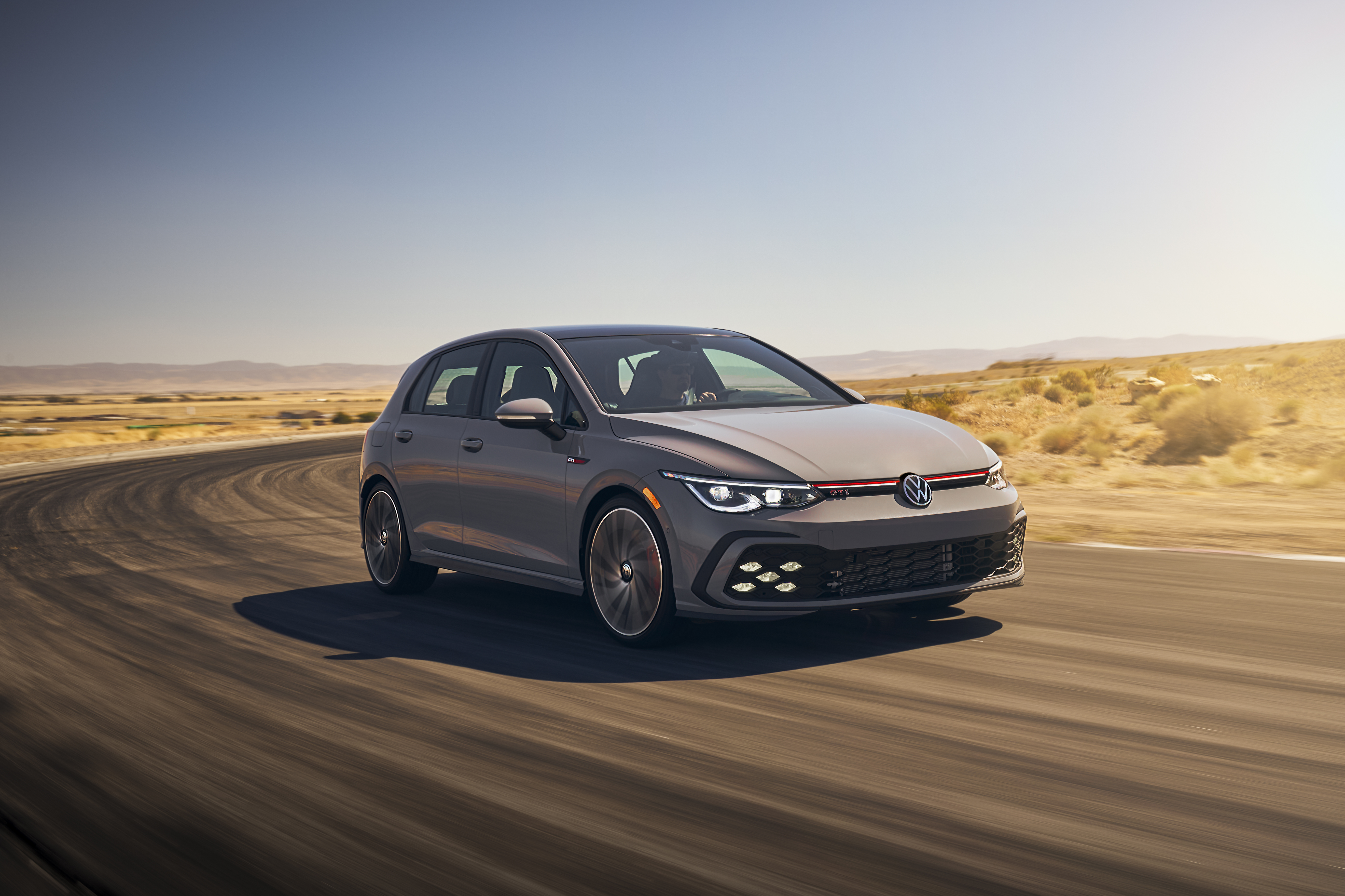 2022 Volkswagen Golf GTI driving on a desert road HD Wallpaper