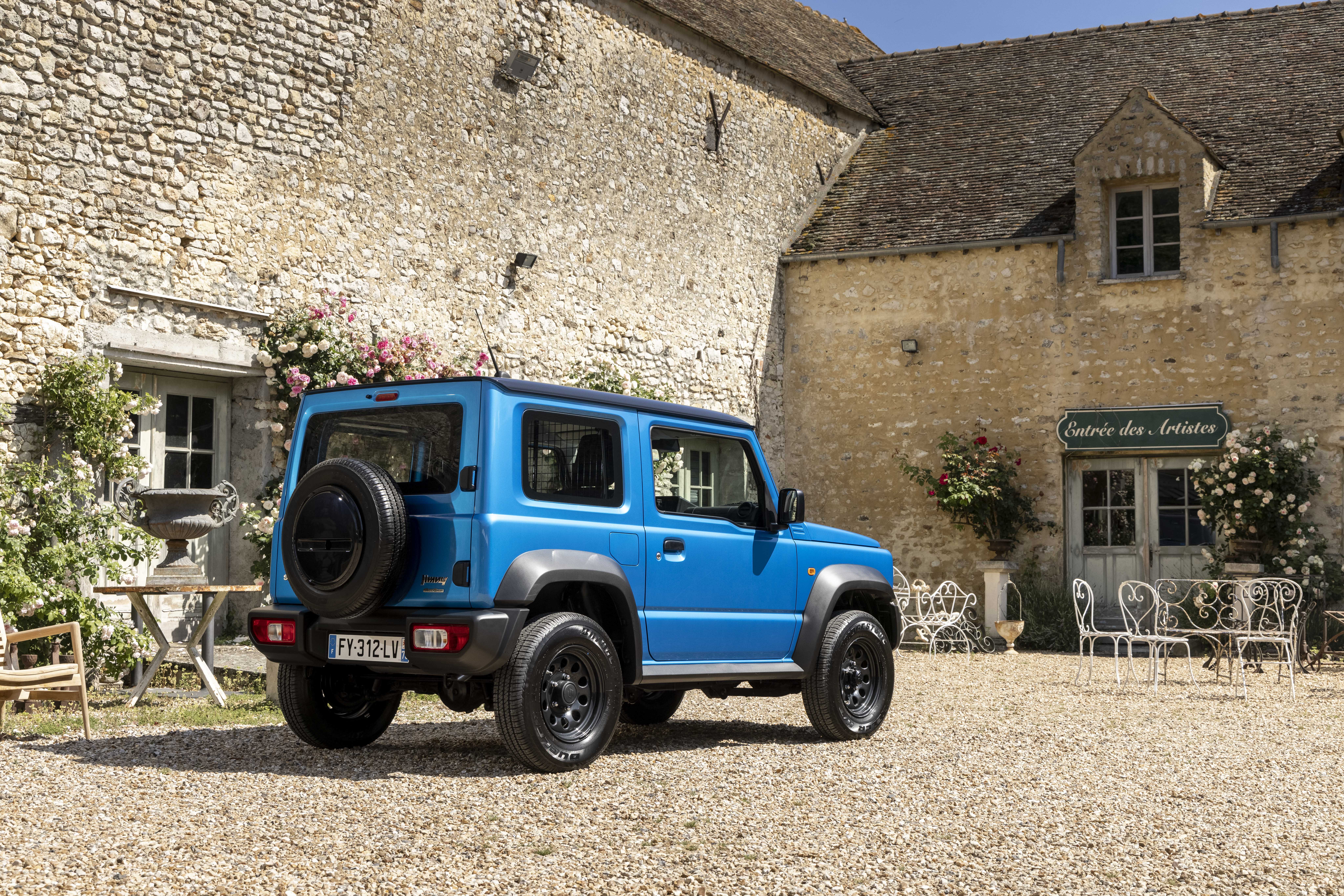 Blue 2021 Suzuki Jimny Commercial parked by stone buildings HD Wallpaper