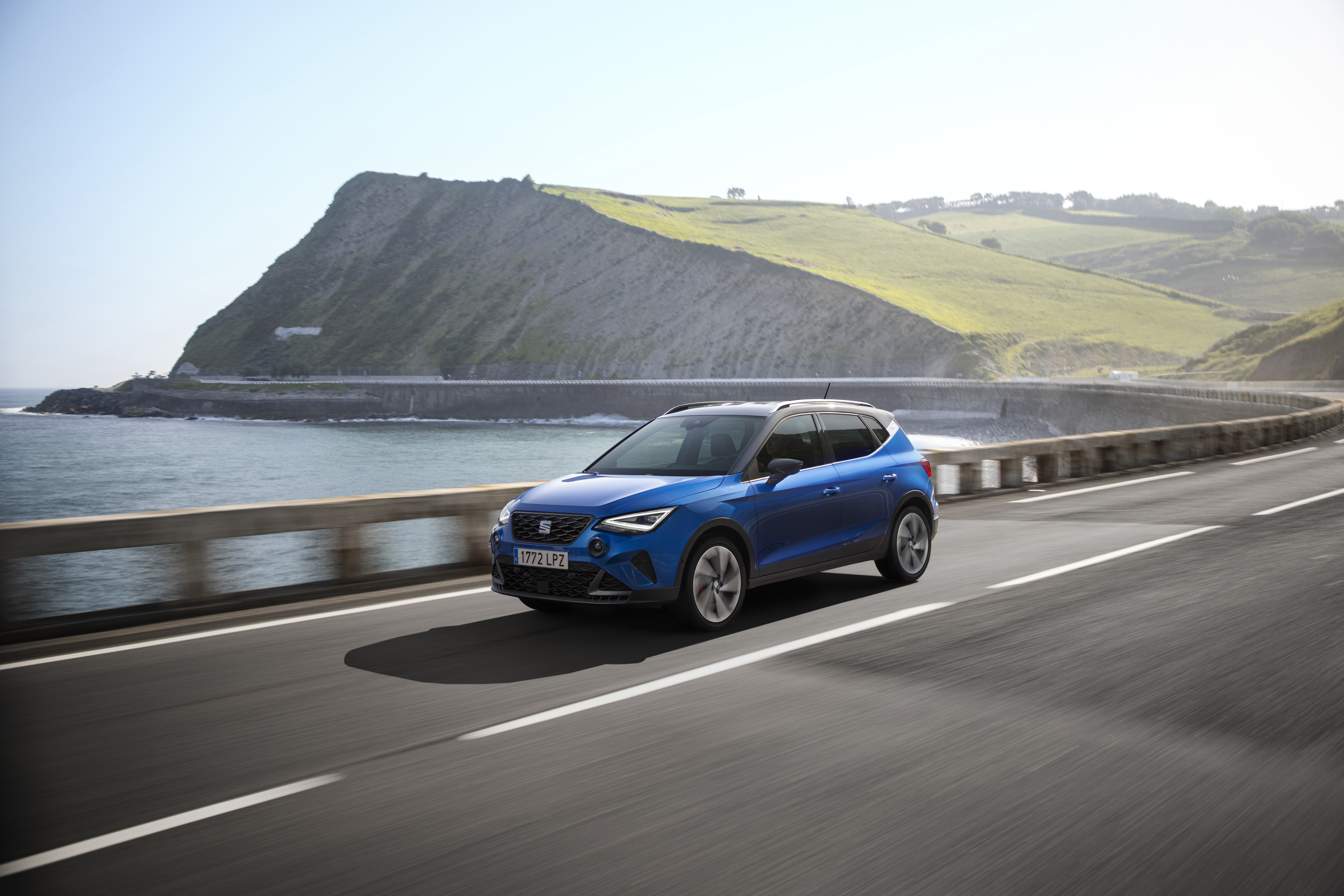 Blue 2021 SEAT Arona FR driving on coastal road HD Wallpaper