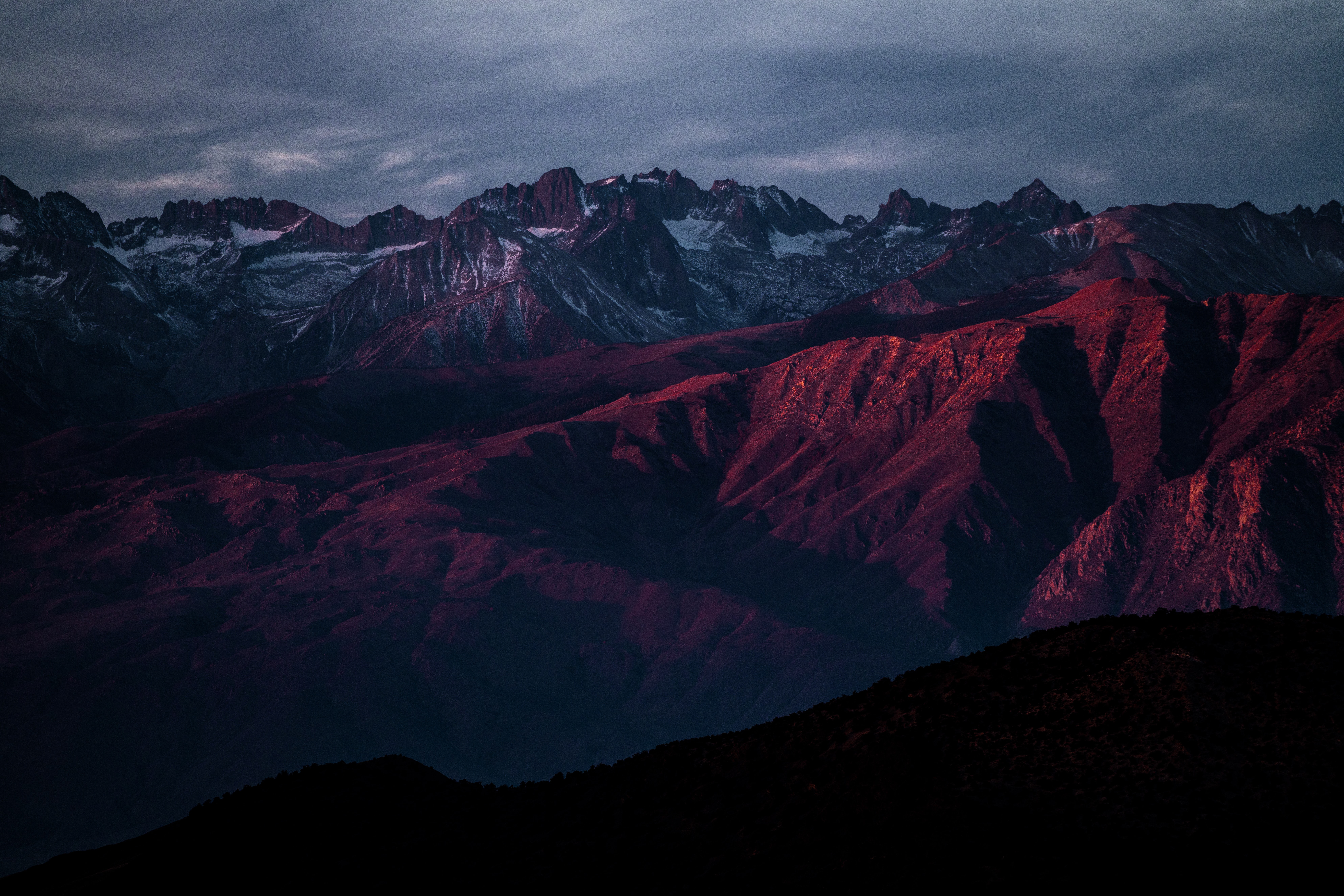 Crimson mountain range under a dramatic twilight sky HD Wallpaper