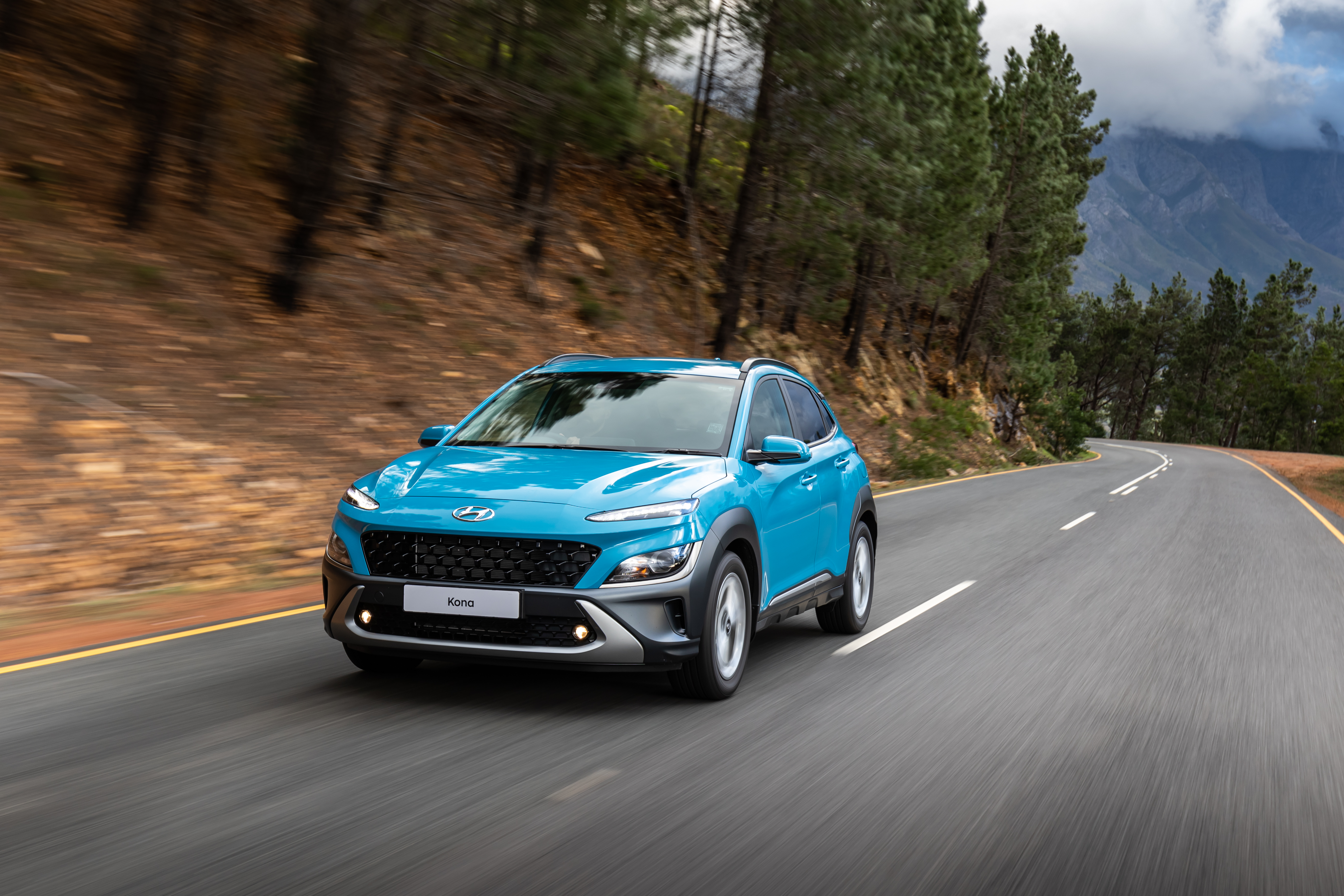 Blue 2021 Hyundai Kona SUV driving on a scenic road HD Wallpaper