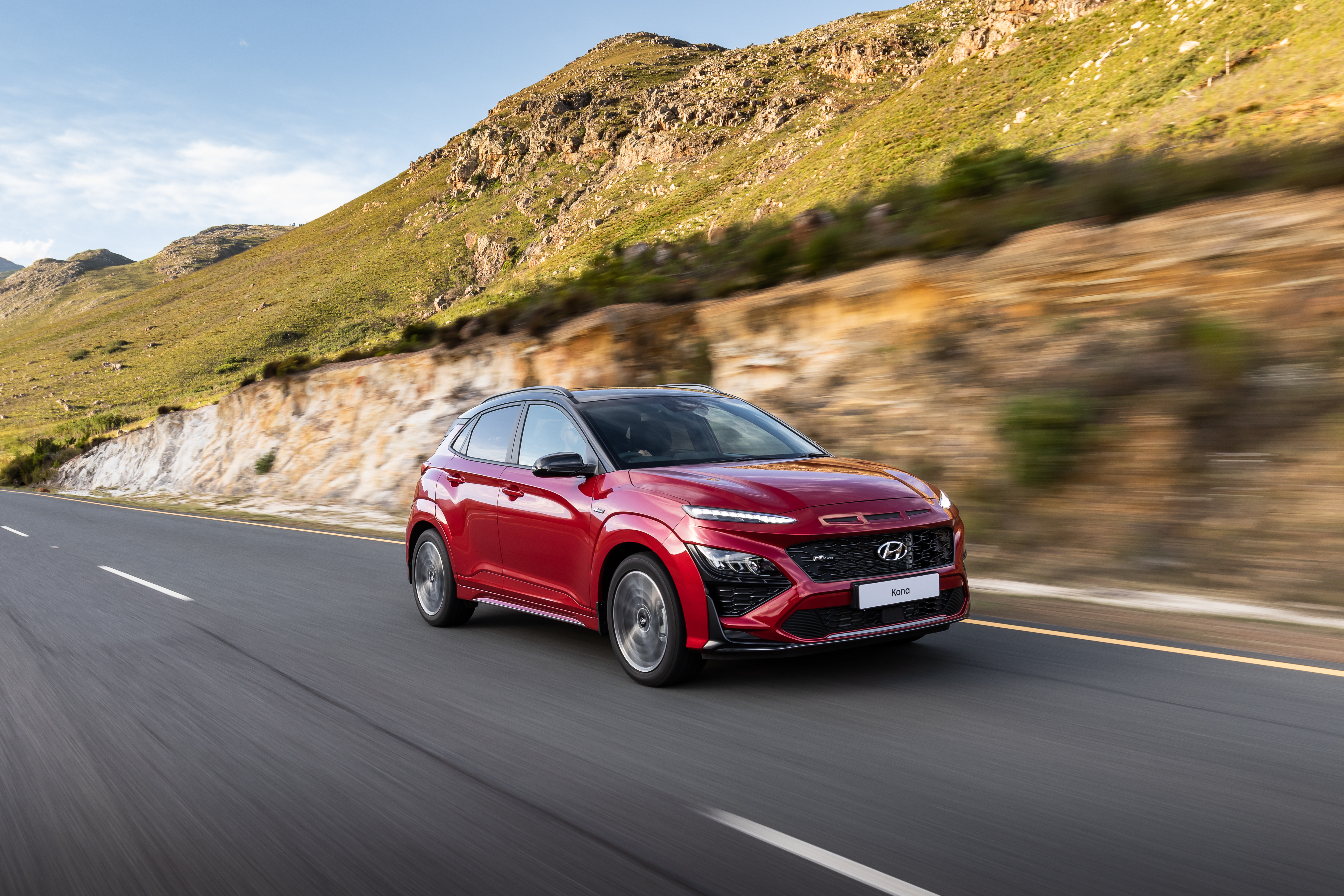 Red 2021 Hyundai Kona N Line driving on a scenic road HD Wallpaper
