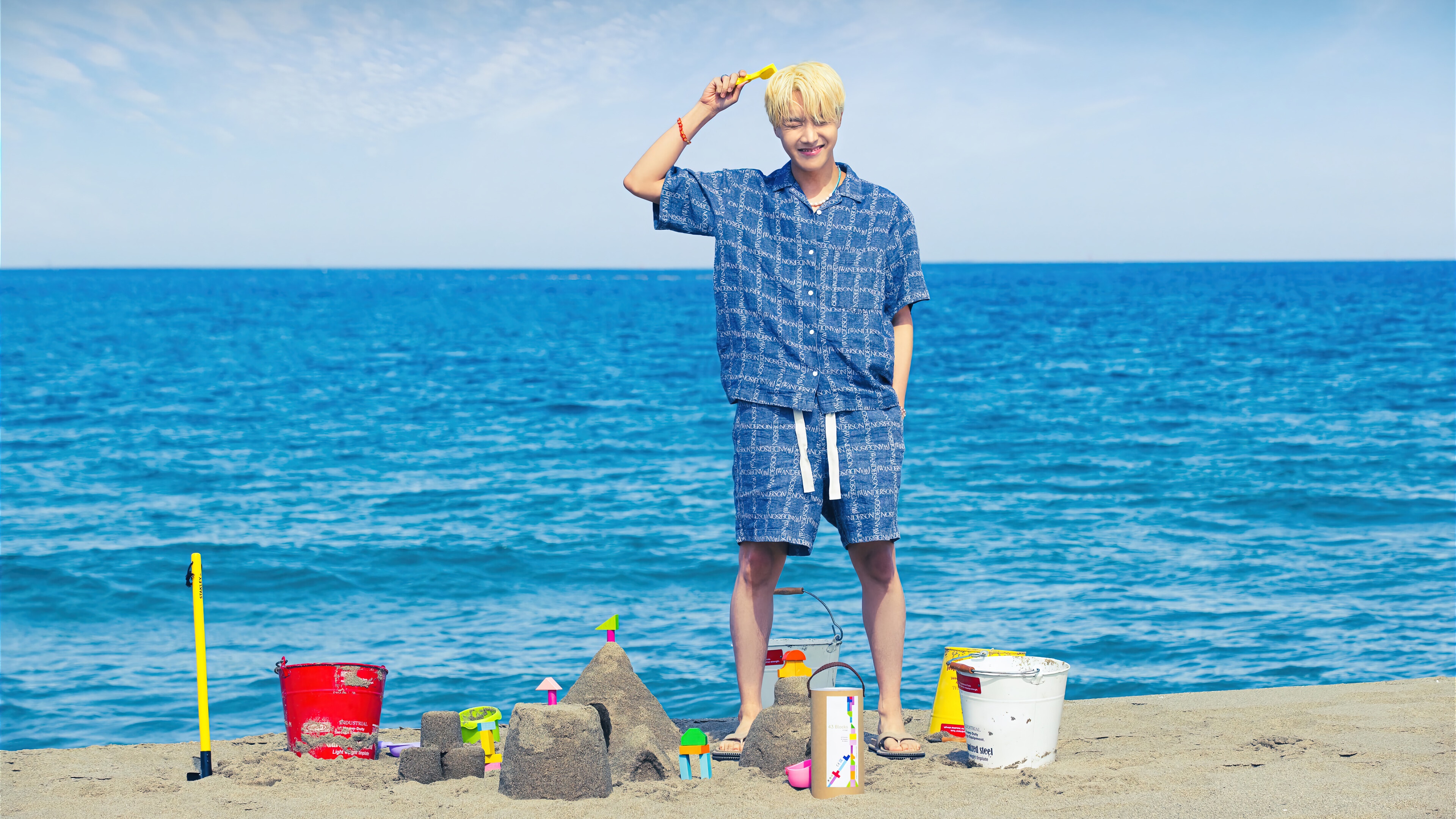 J-Hope from BTS on a beach with sandcastle toys HD Wallpaper