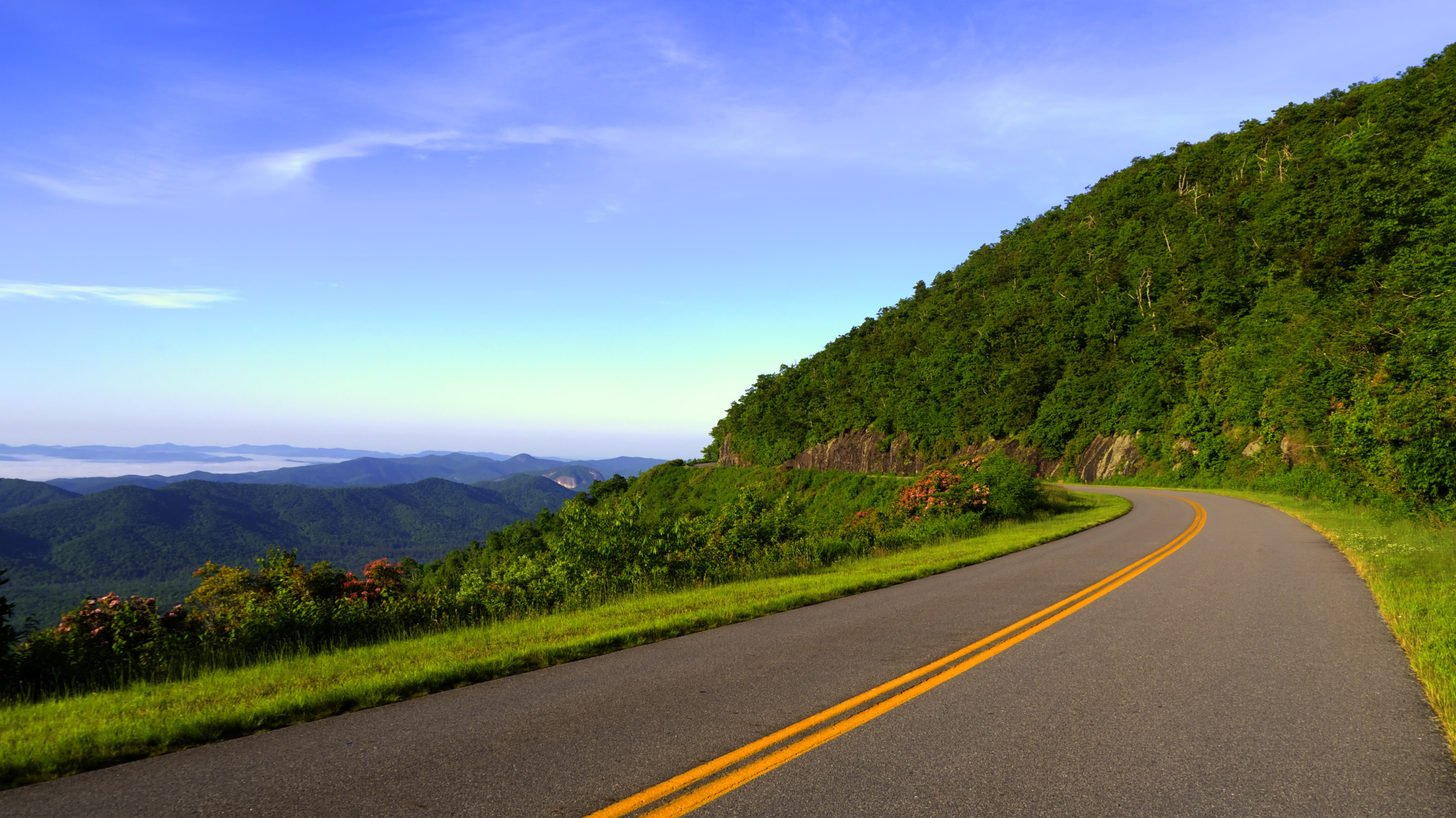 Scenic mountain road with double yellow lines HD Wallpaper