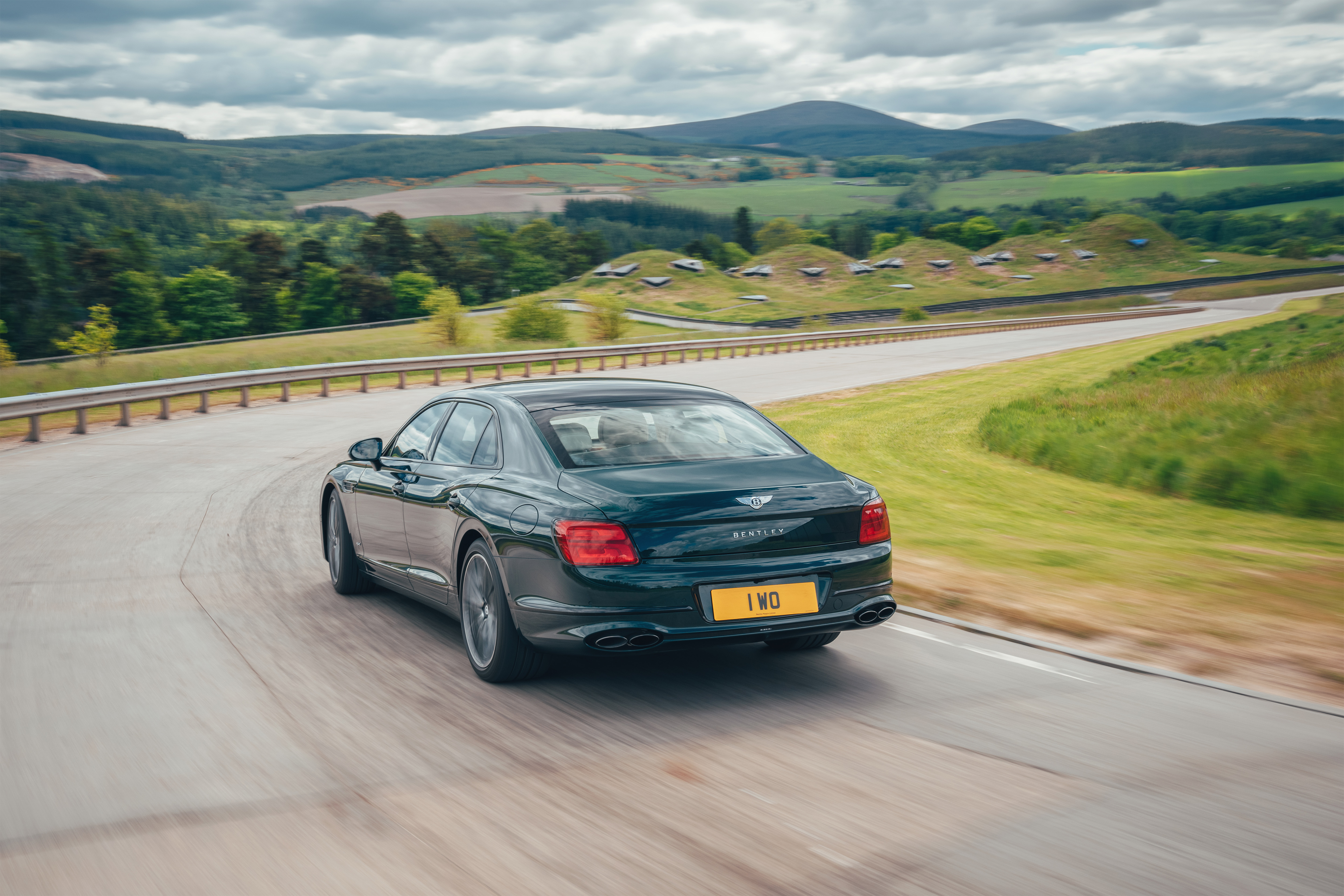 Green Bentley Flying Spur Hybrid driving on a scenic road HD Wallpaper