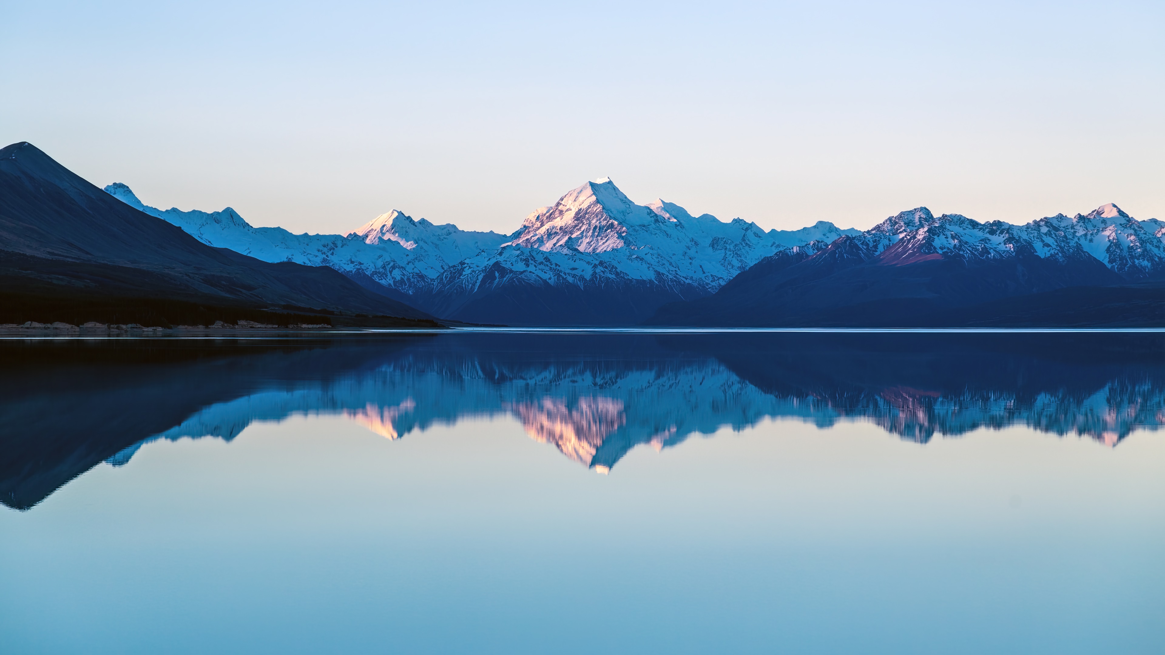 Snow-capped mountains reflected in a calm lake HD Wallpaper