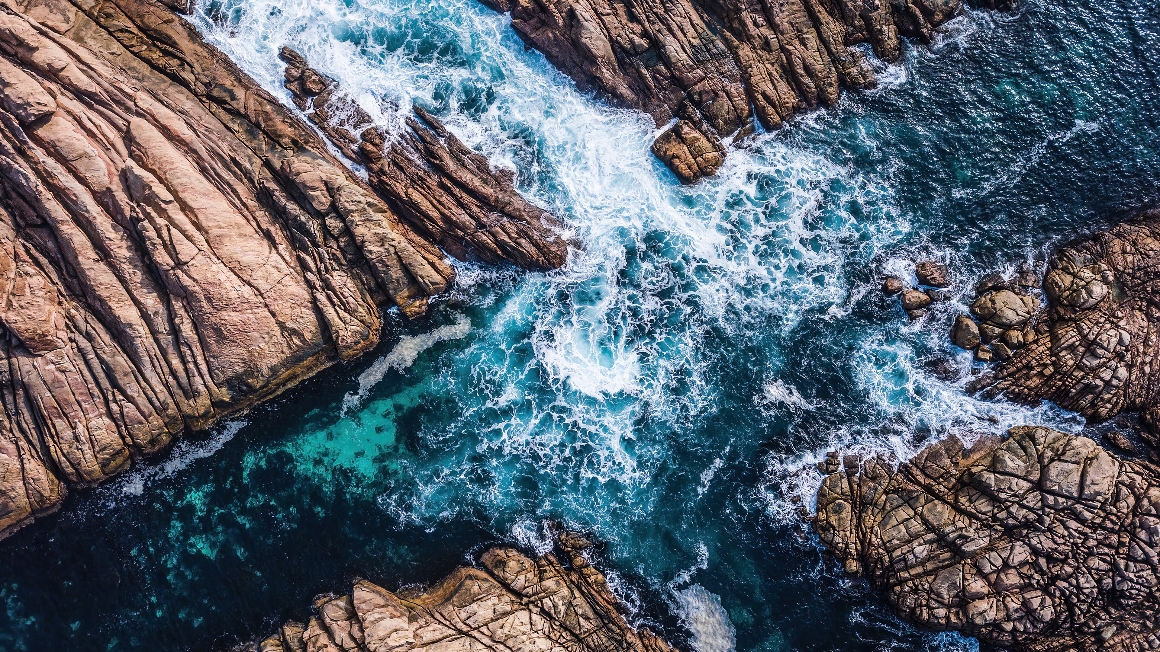 Aerial view of ocean waves crashing on rocky coastline 4K HD Wallpaper